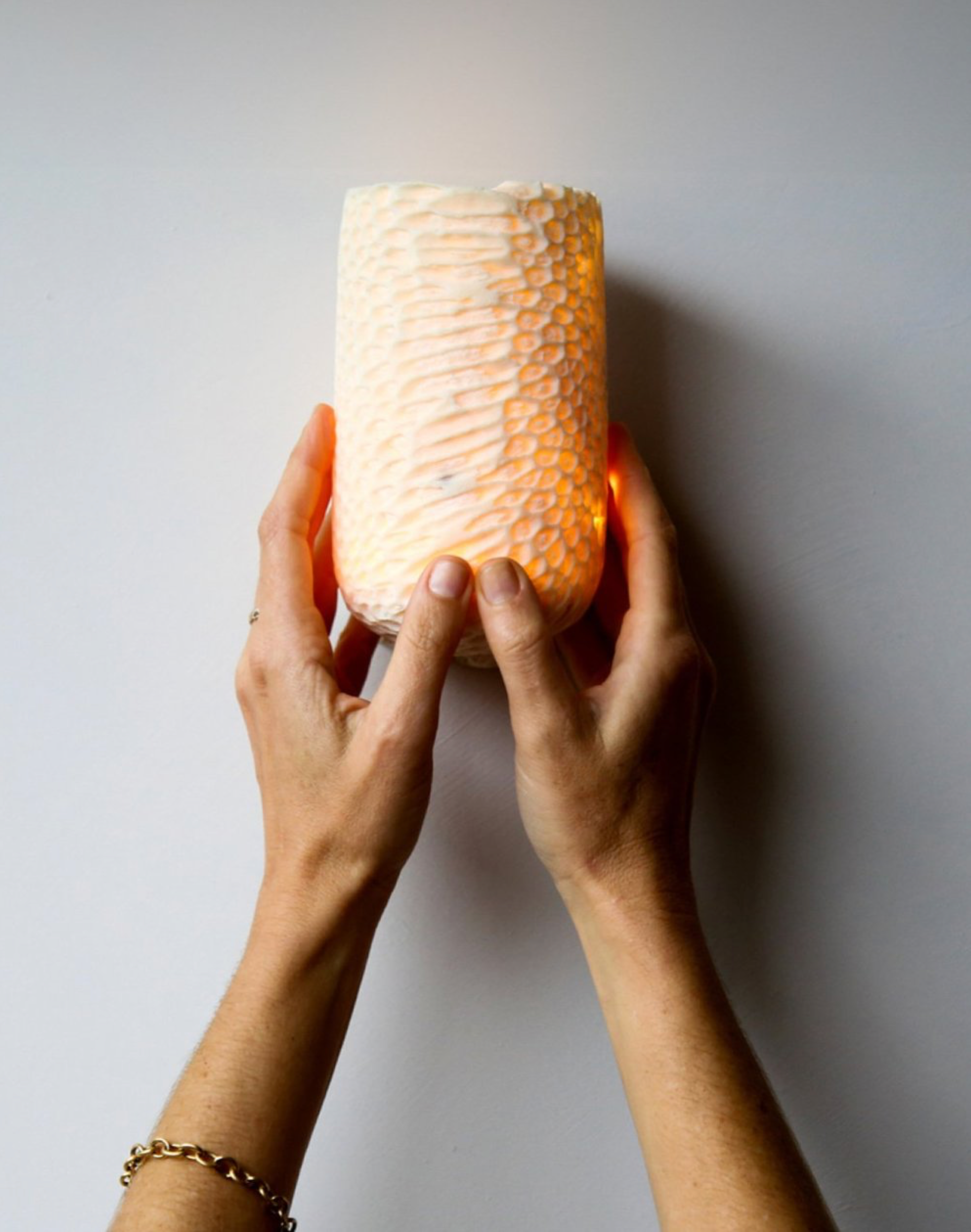 Person holding a textured wall light against a plain background