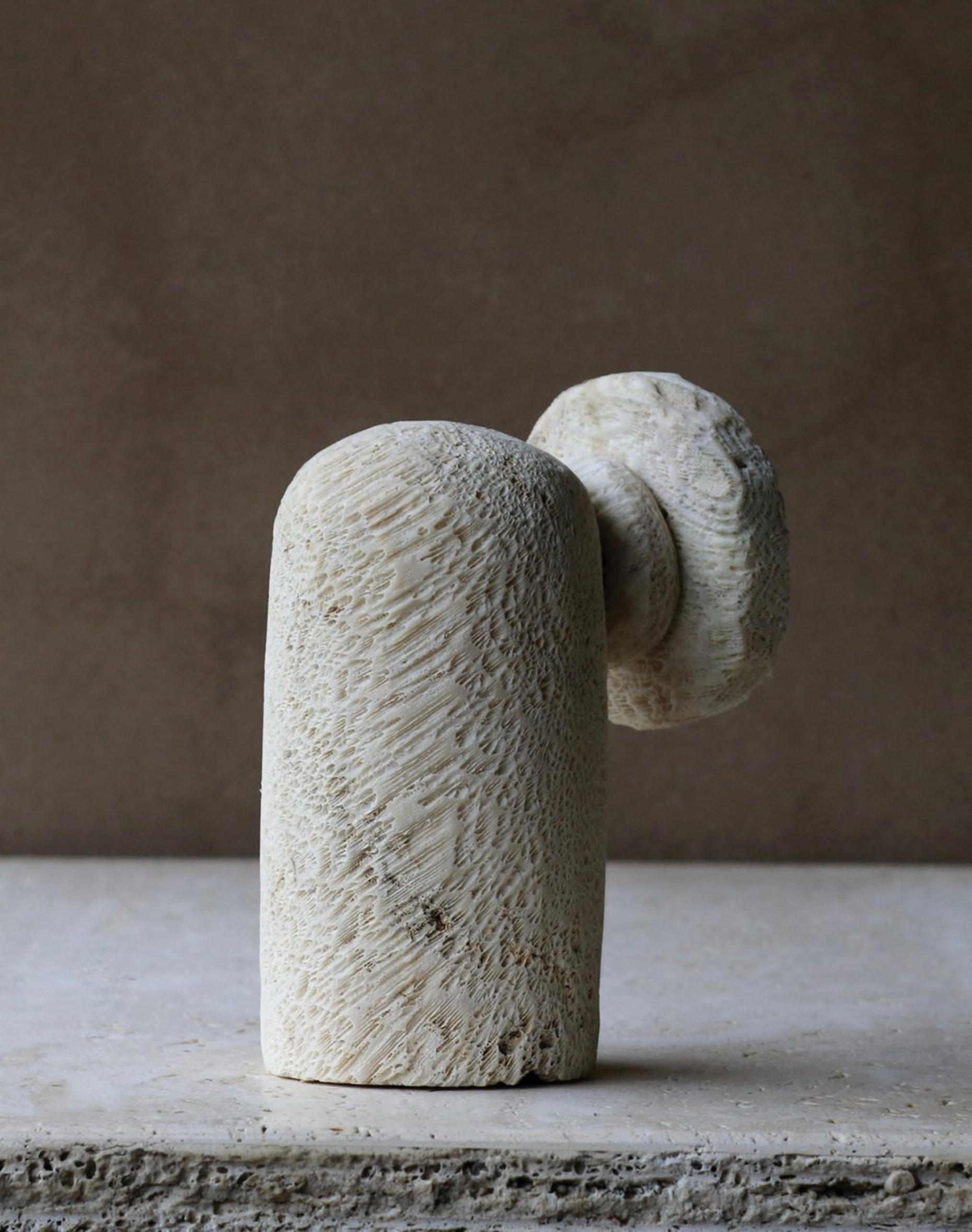 Abstract stone sculpture on a textured surface with a neutral background