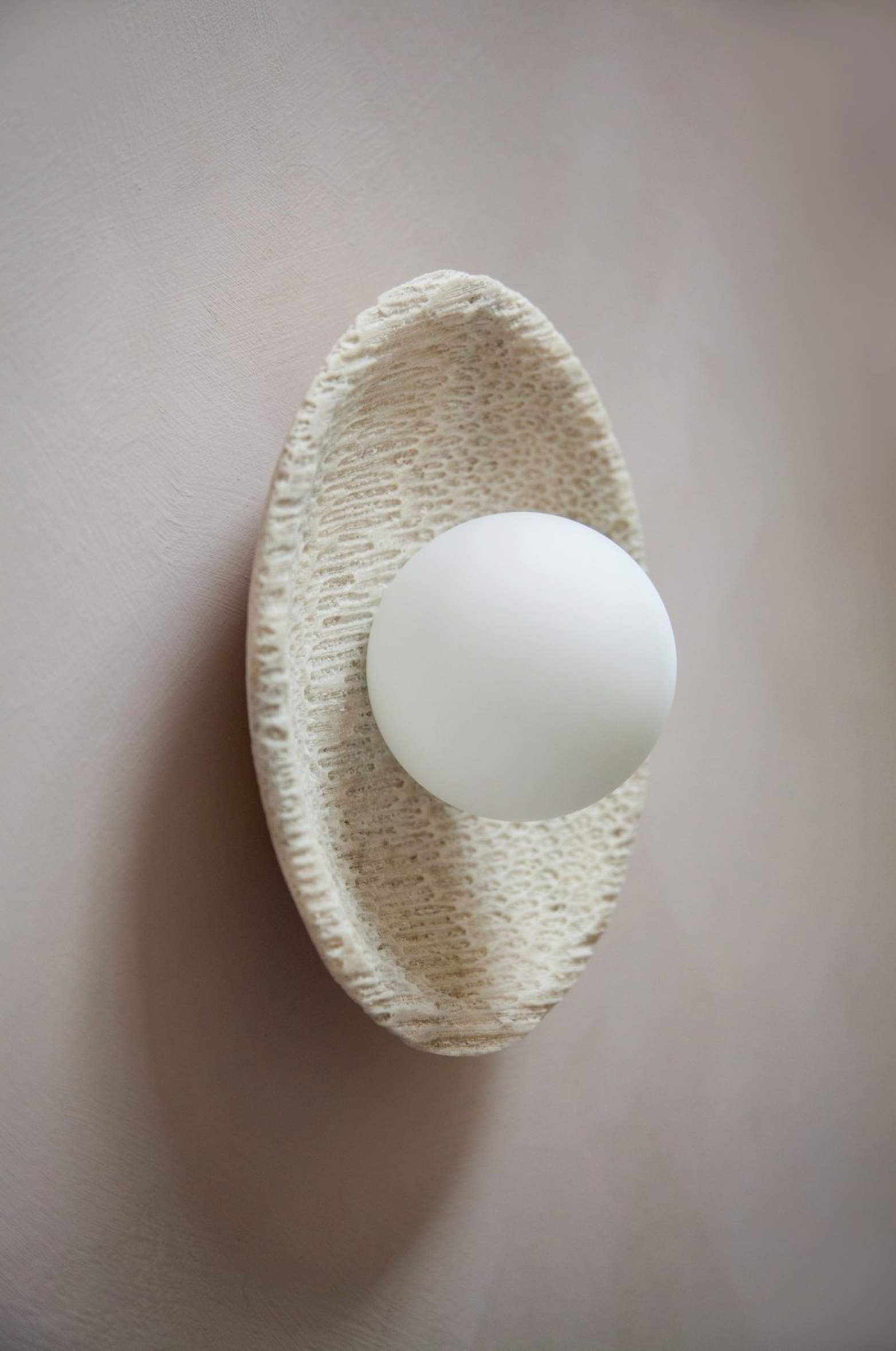 White spherical object in a woven beige holder on a light gray background
