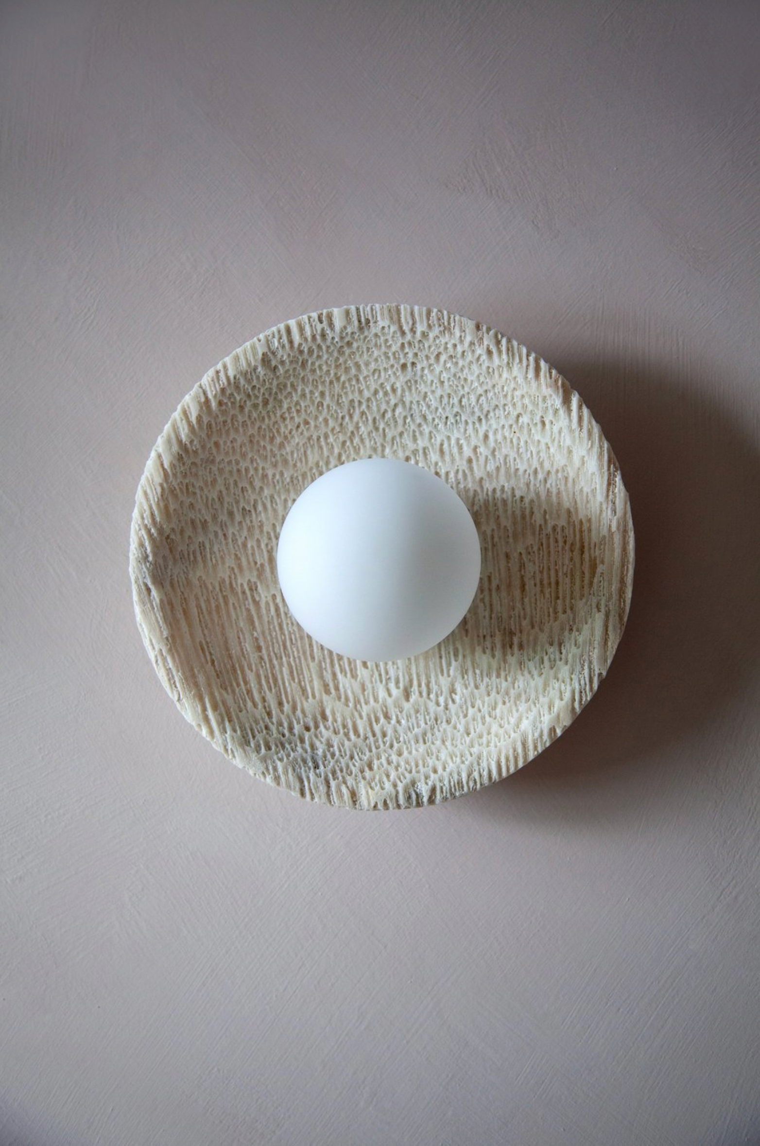 White ball on a textured coral beige plate against a grey background