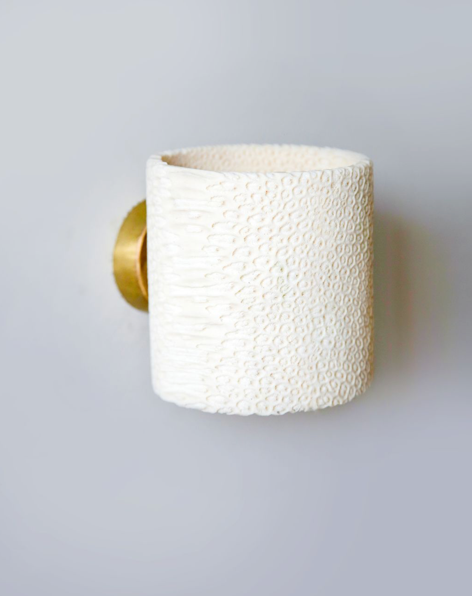 White textured wall light with gold base on a light grey background