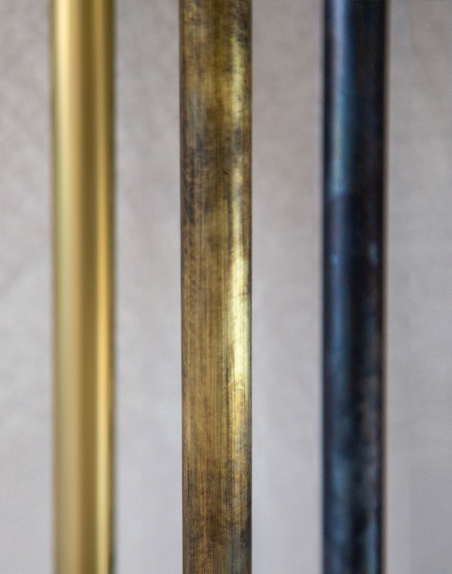 Three vertical metal bars of different colors on a grey background