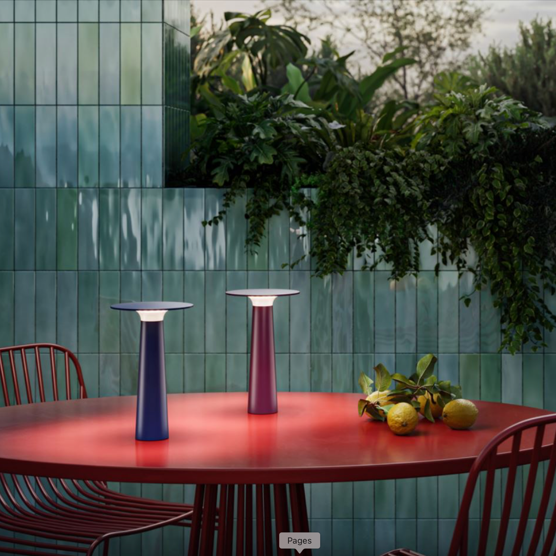 Outdoor setting with a red table, purple stools, and greenery against a tiled wall.