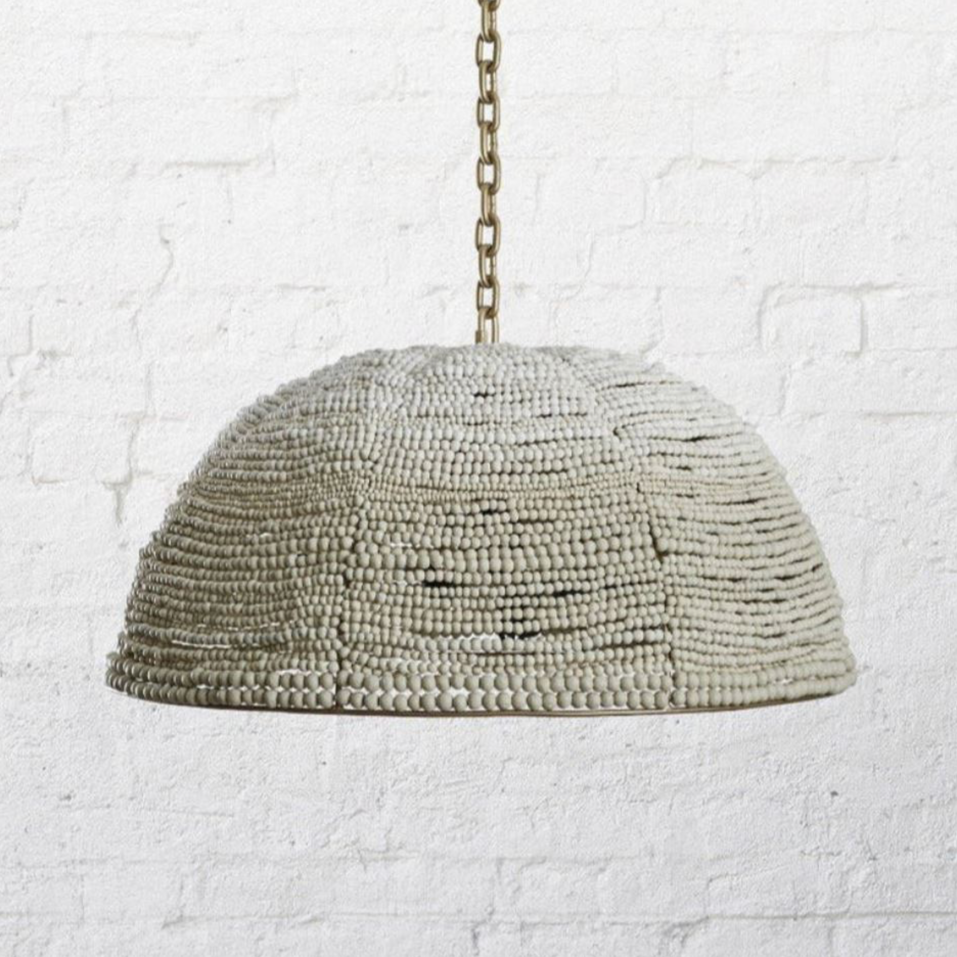Textured dome pendant light hanging against a textured white wall