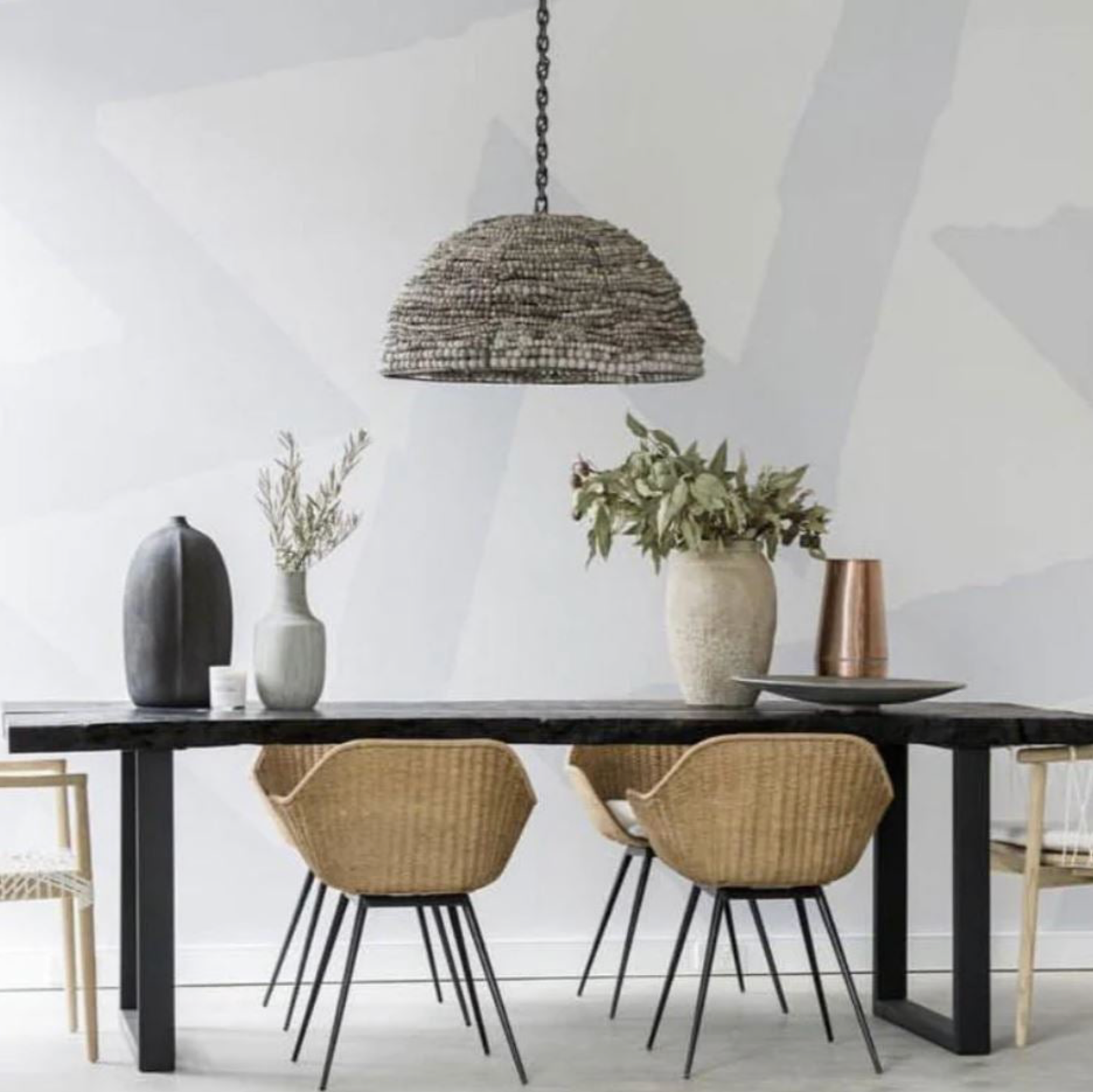 Dining area with a black table, wicker chairs, and decorative vases in a modern interior.