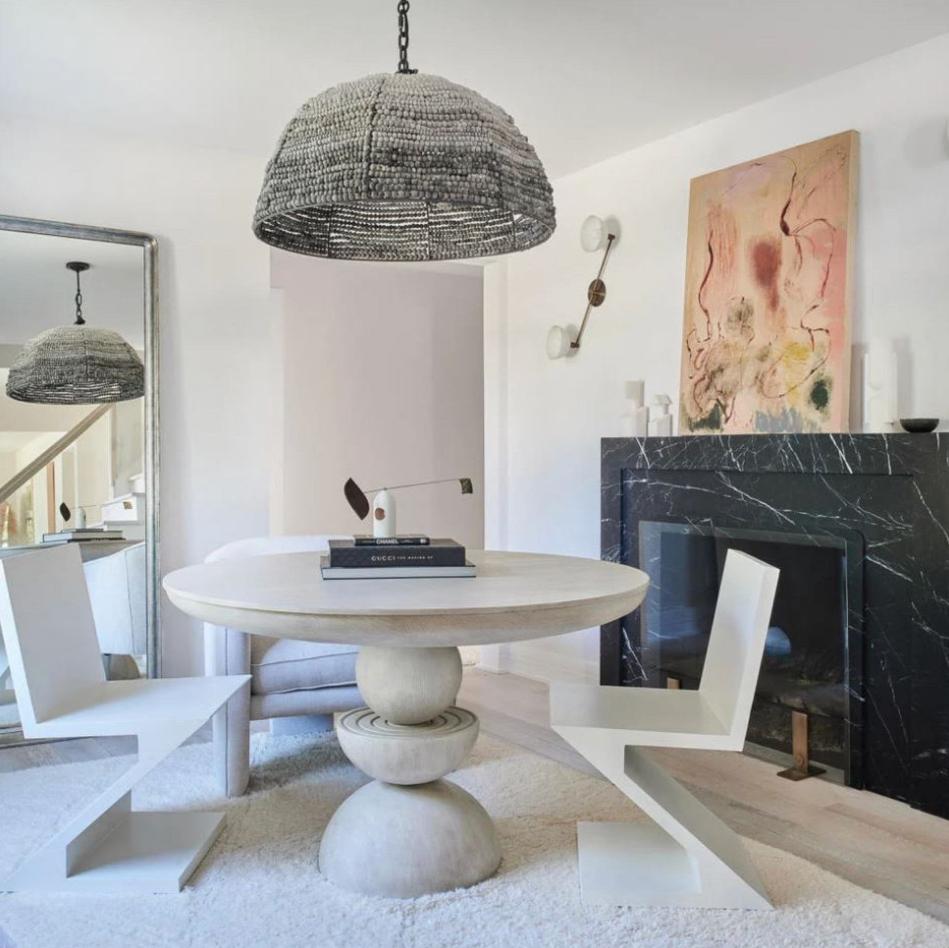 Modern living room with a round marble table, abstract art, and a textured pendant light.