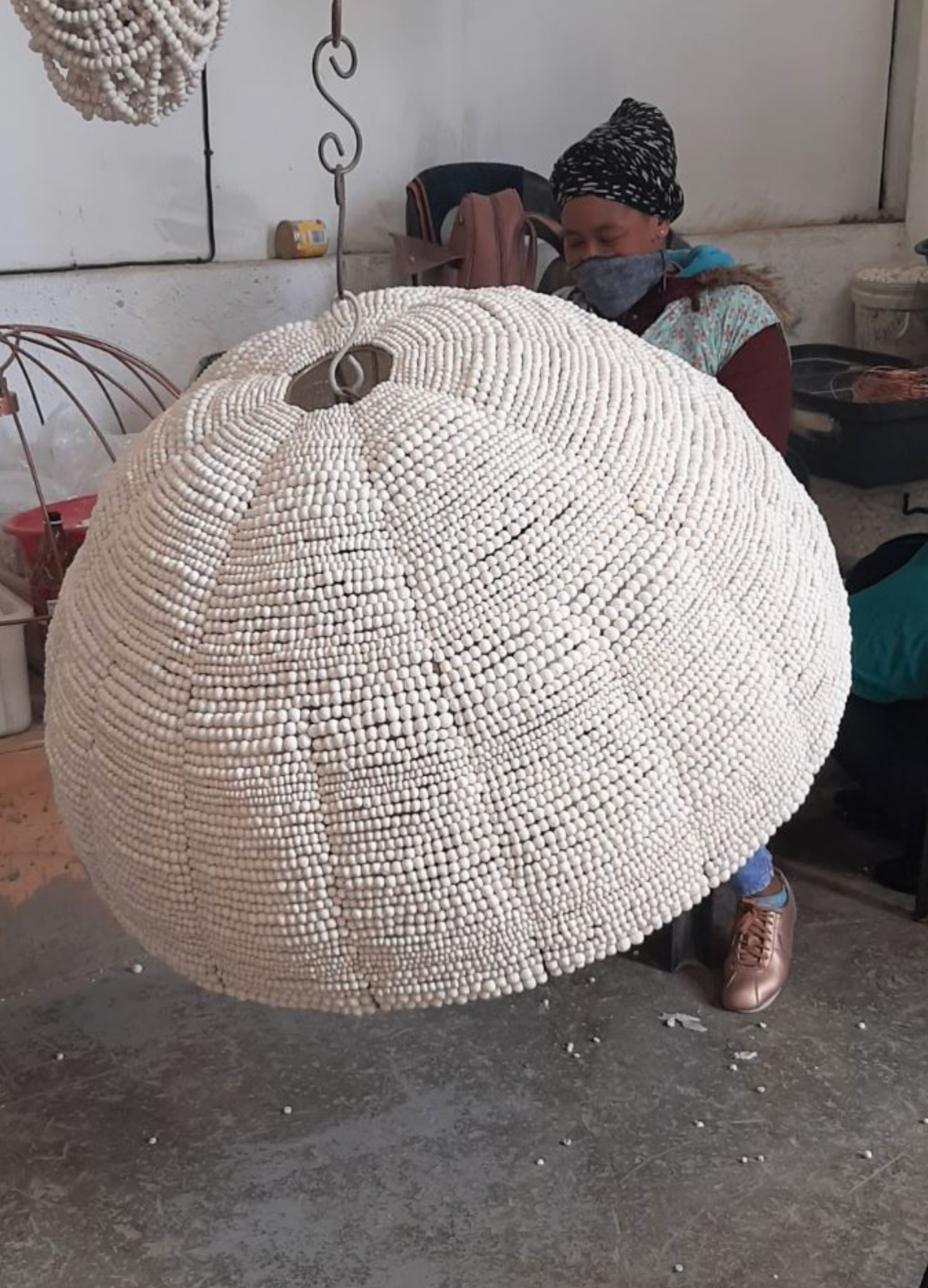 Large woven clay pendant  in a workshop setting with a person in the background.