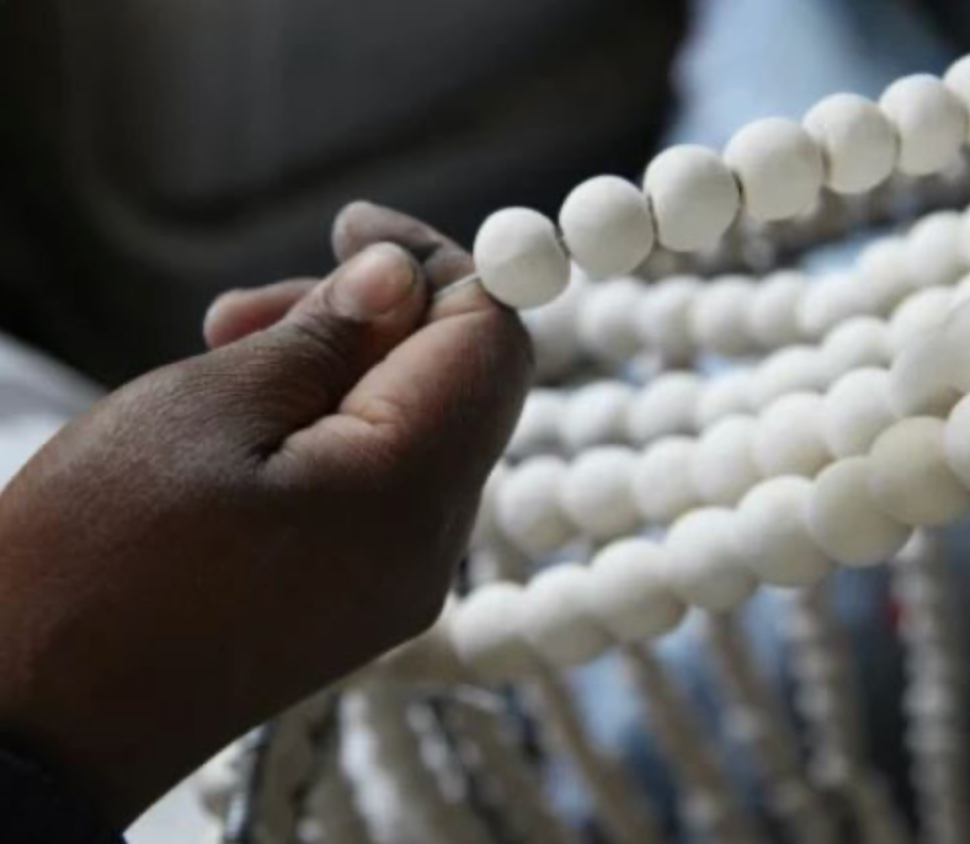 Close-up of a hand holding a white beads against a blurred background