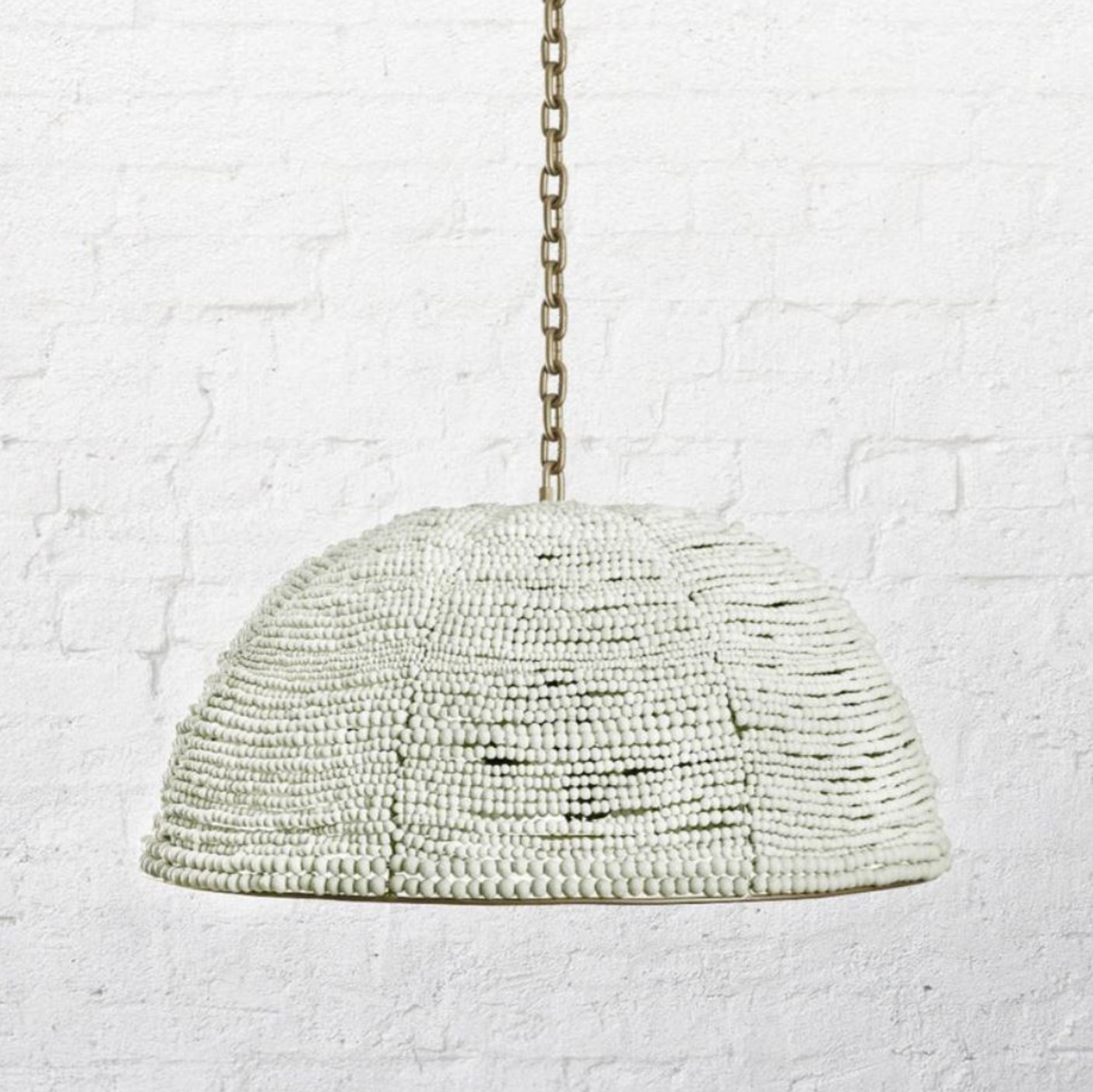 Beaded pendant light hanging against a textured white wall