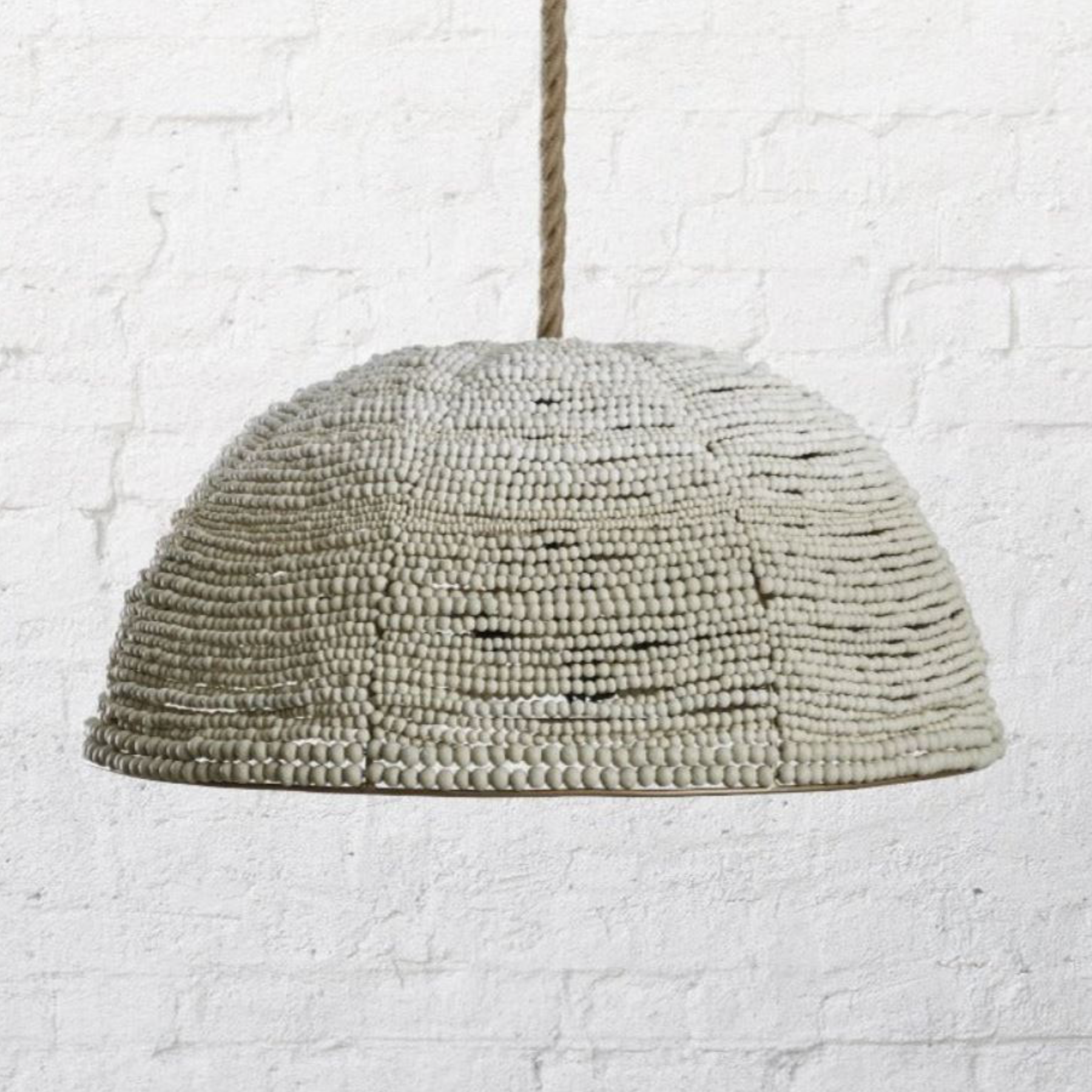 Textured pendant light fixture against a white brick wall.
