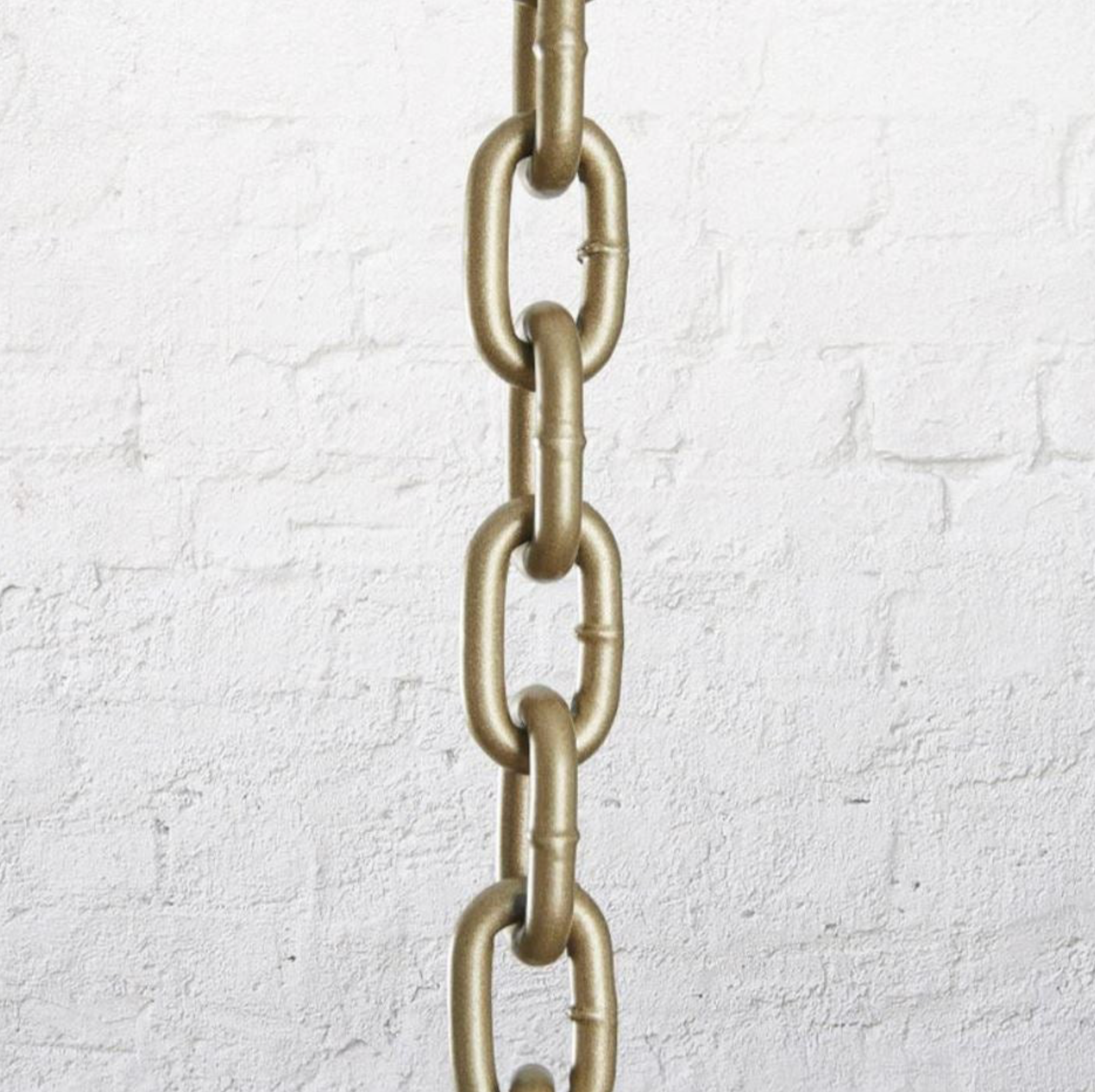 Brass pendant chain against a white textured wall