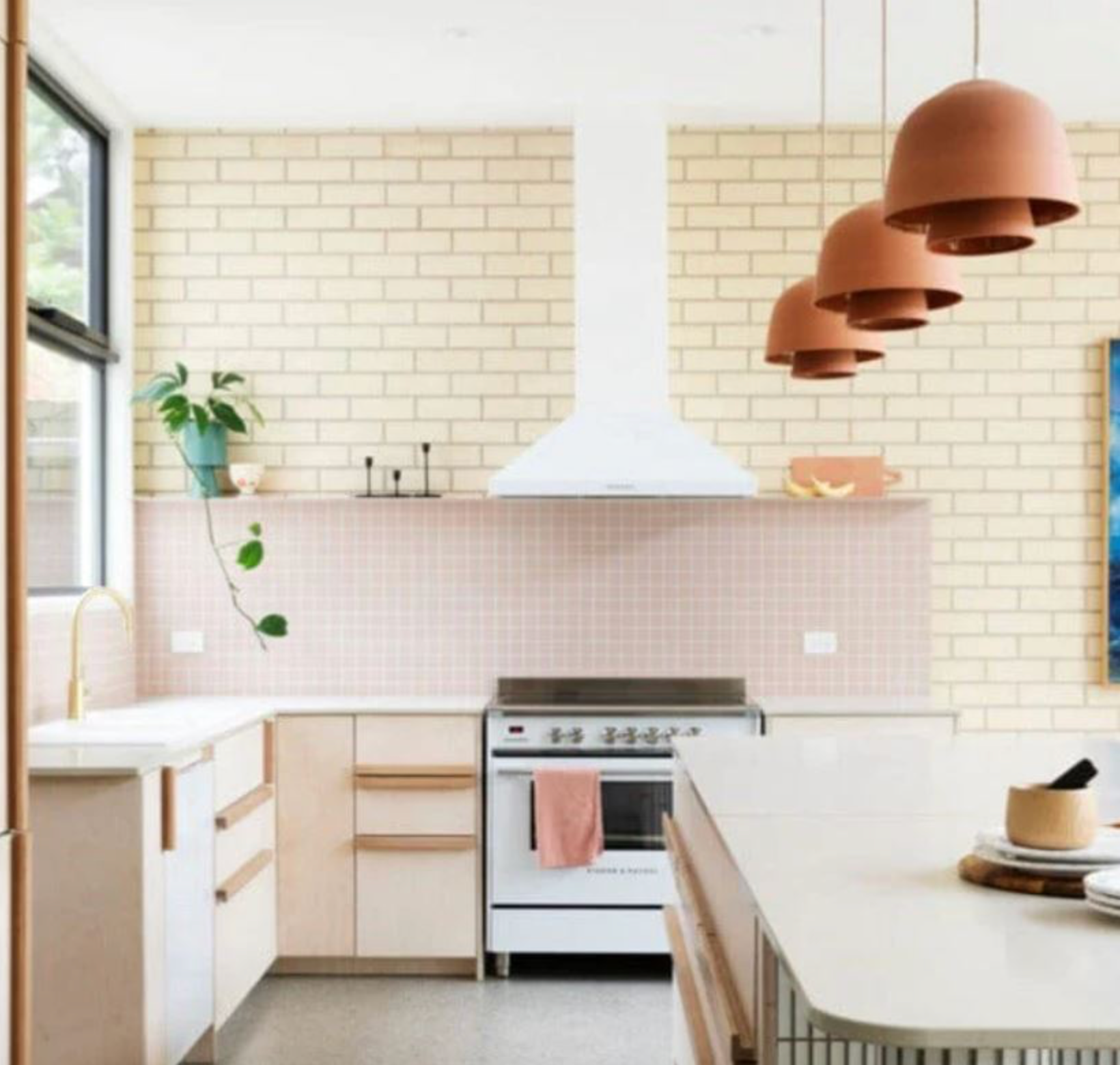 Modern kitchen with white tiled walls, wooden cabinets, and clay pendant lights.