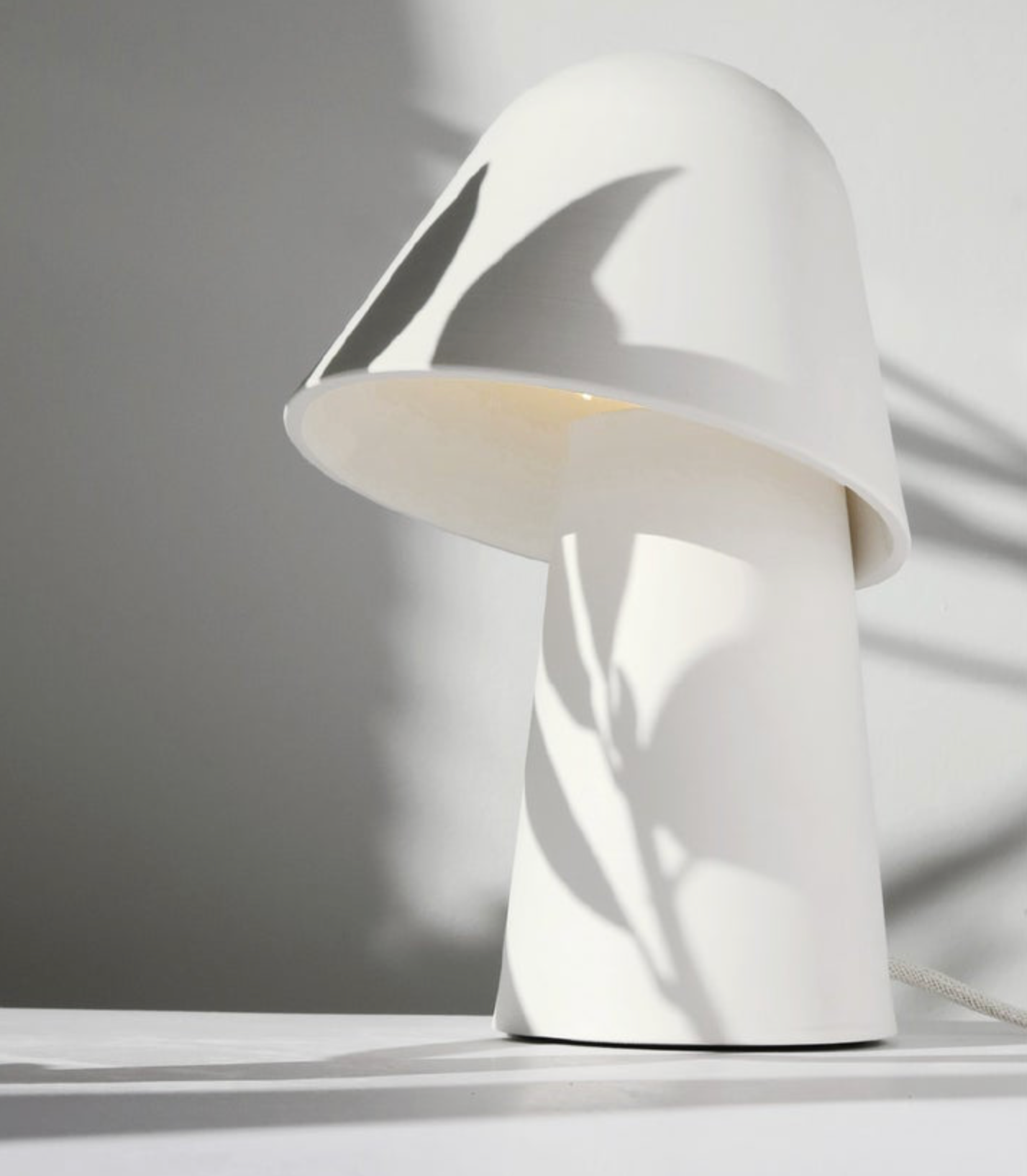 White clay lamp with a unique design on a light shadow background