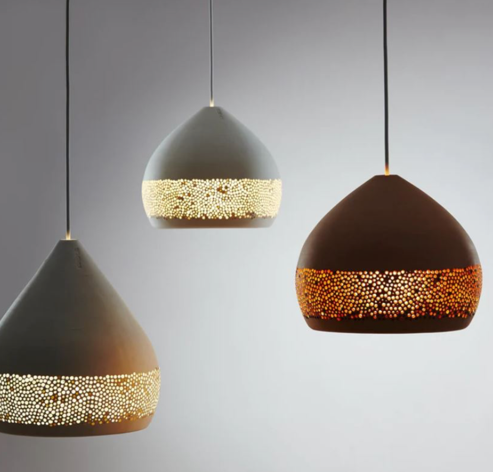 Three modern pendant lights with textured interiors on a gray background