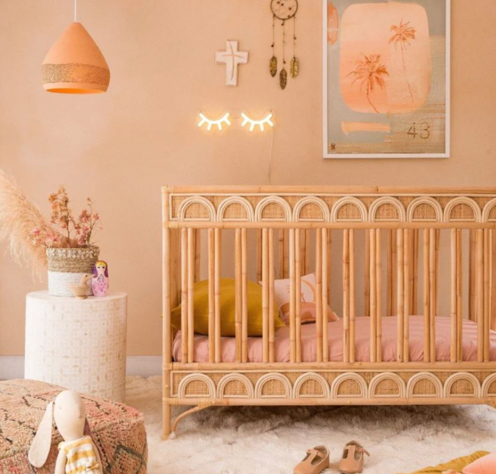 Nursery room with a wooden crib, decorative items, and a pendant lamp.