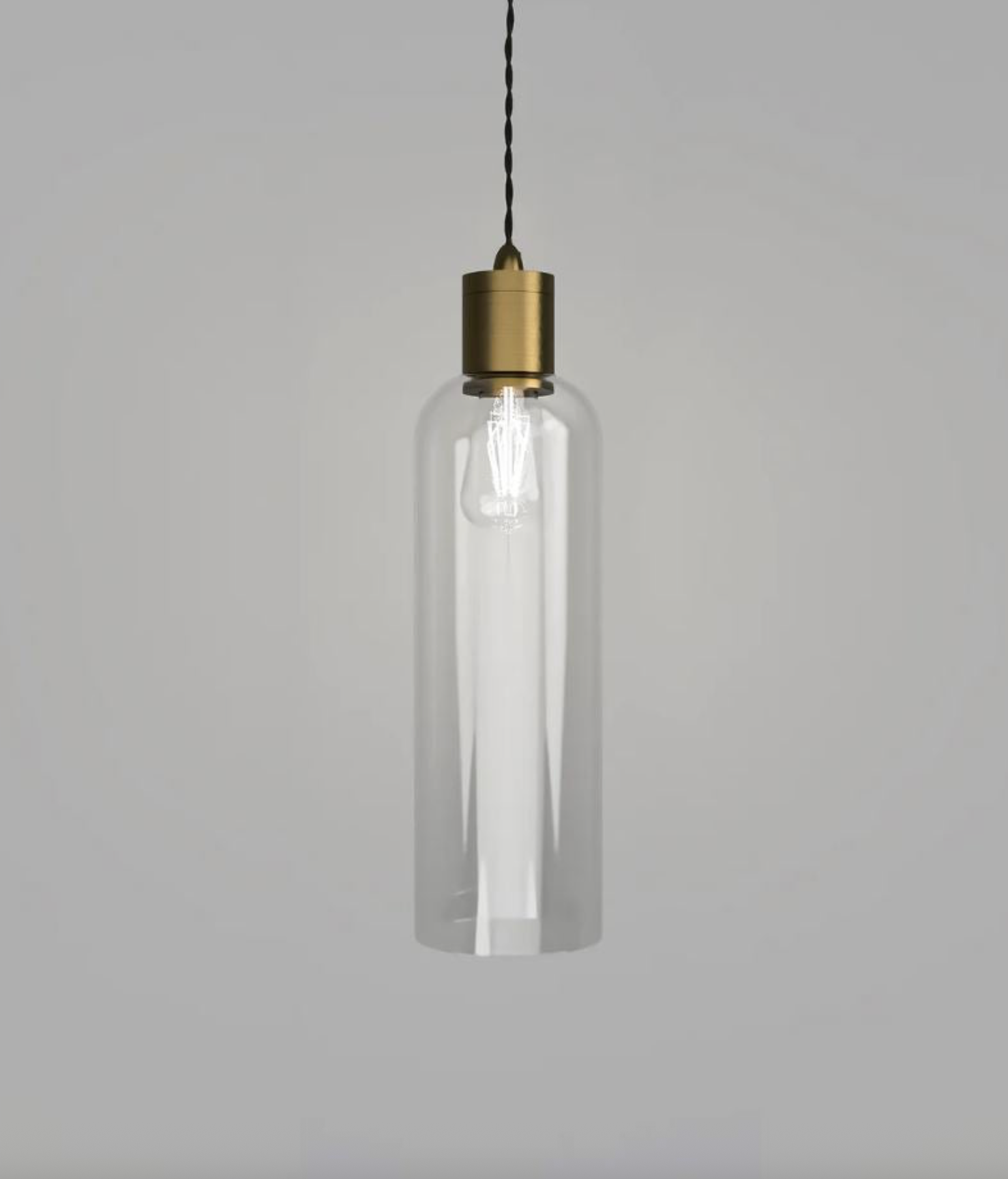 Clear glass pendant light with brass fixture on a gray background