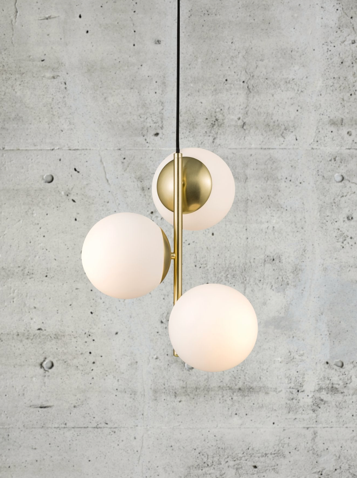 Modern pendant light with three spherical glass shades on a concrete wall background