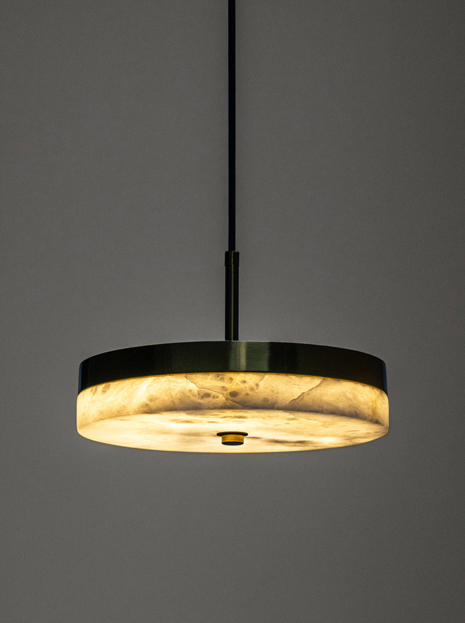 Modern pendant light with a black frame and gold interior on a grey background