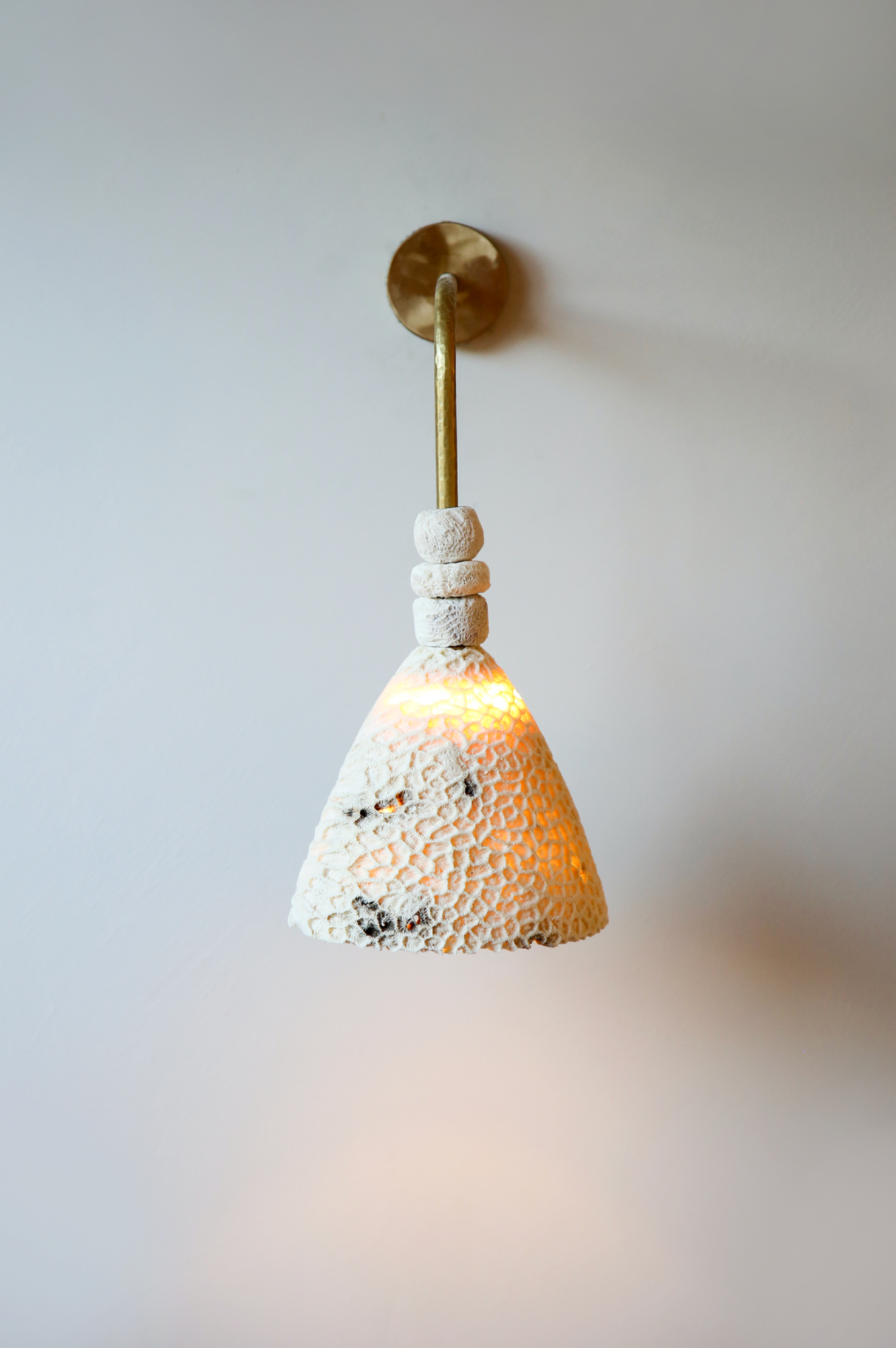 Wall-mounted light fixture with textured ceramic shade on a plain wall