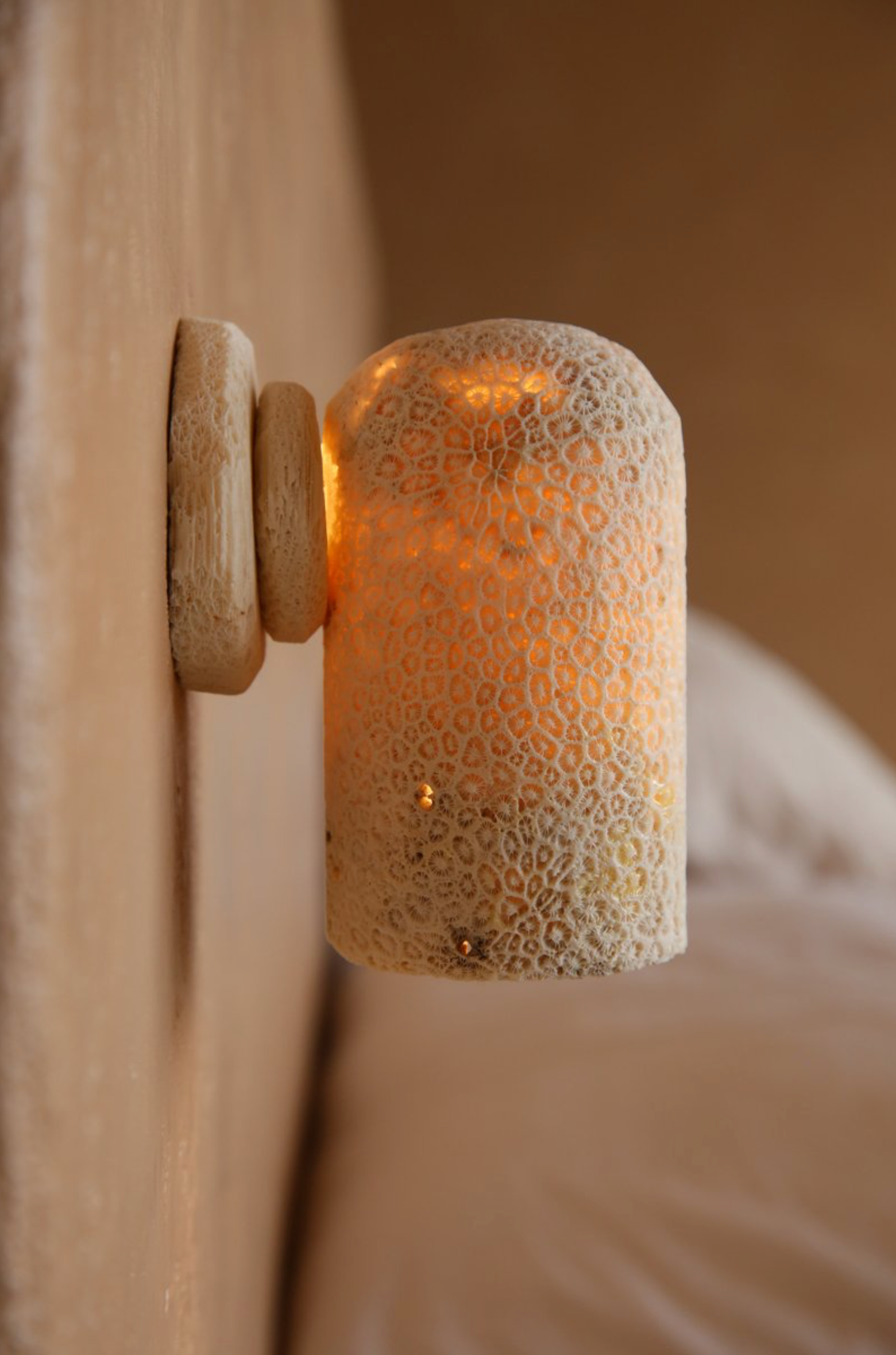 Decorative wall light fixture with textured glass shade on a neutral background