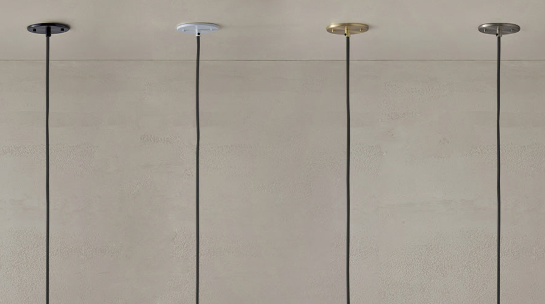 Four pendant lights hanging from a ceiling against a plain wall.