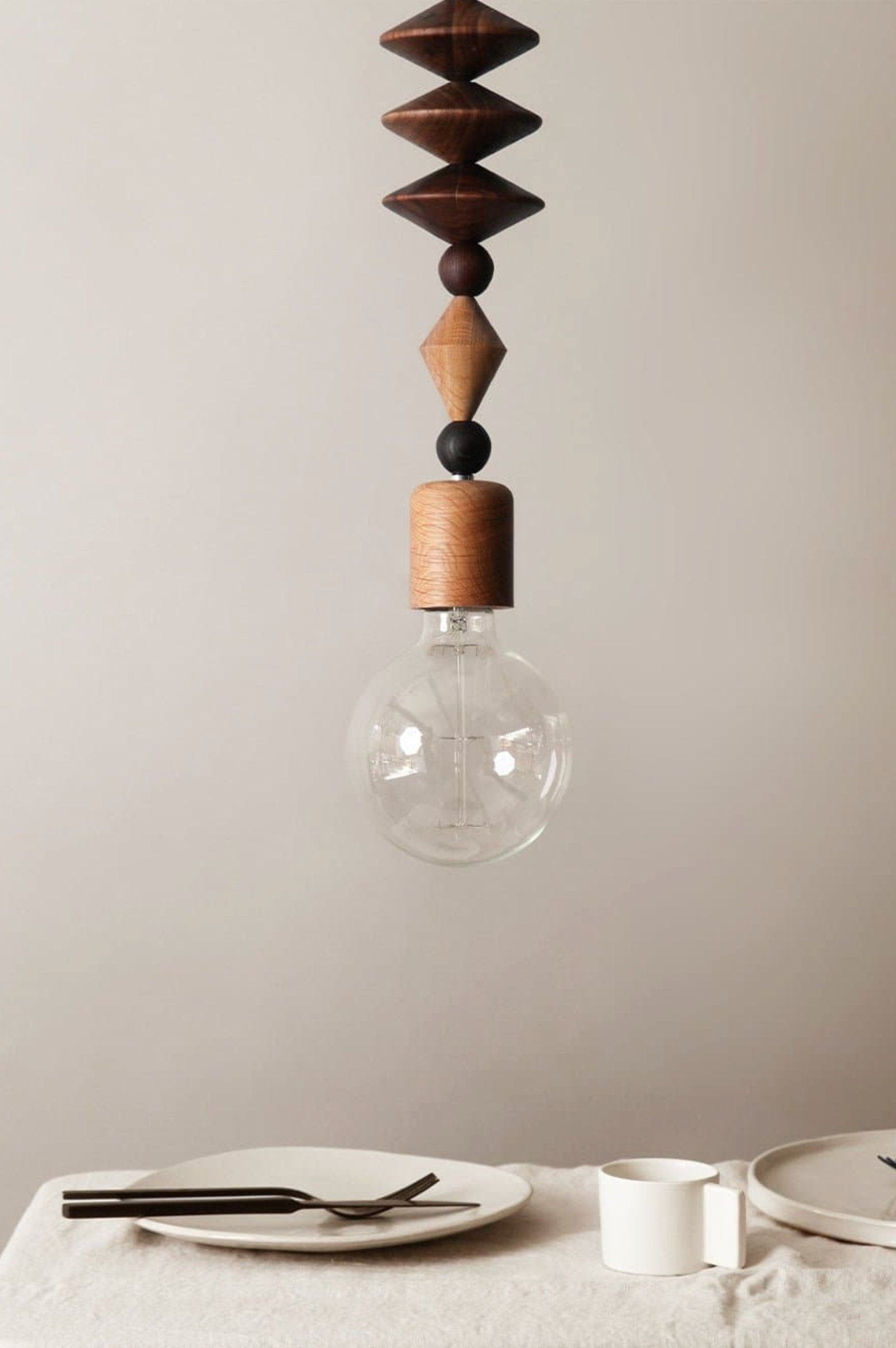 Wooden pendant light with a clear bulb on a neutral background