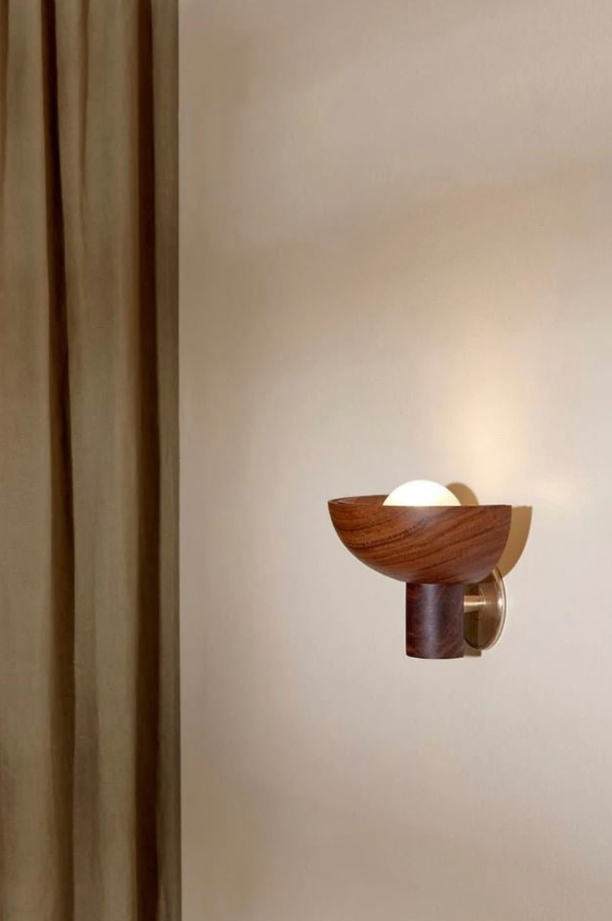 Wooden wall sconce on a beige wall with a curtain partially covering it