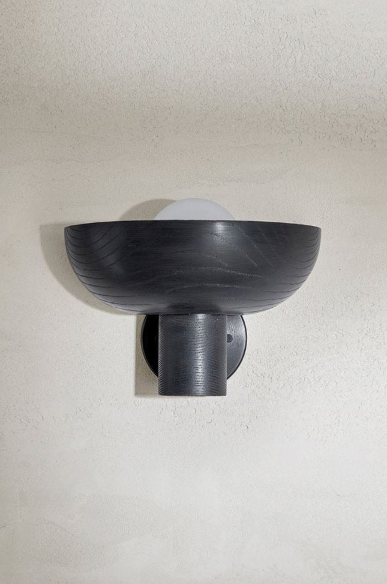 Black wall-mounted light fixture on a white wall