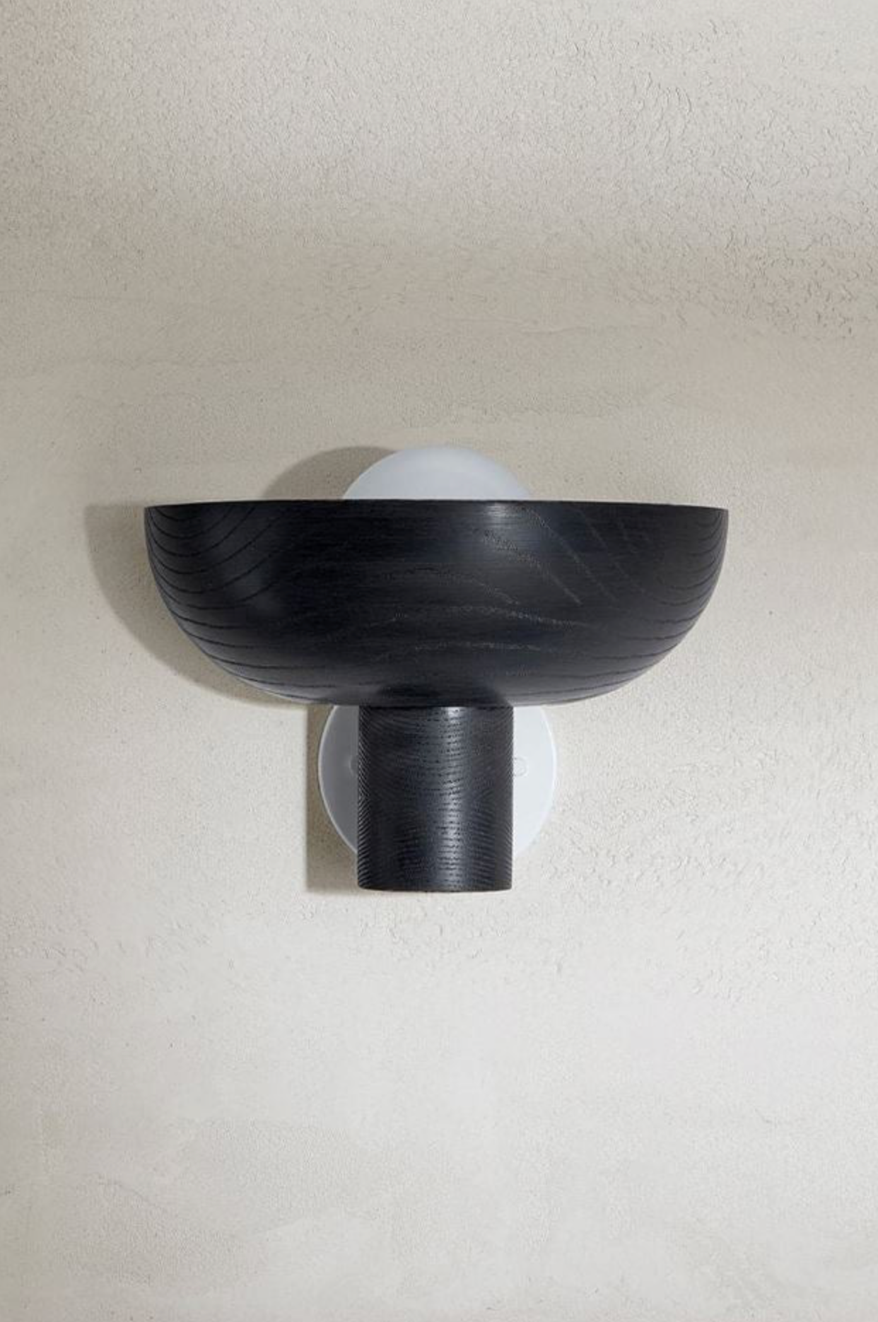 Black wall-mounted light fixture on a beige wall