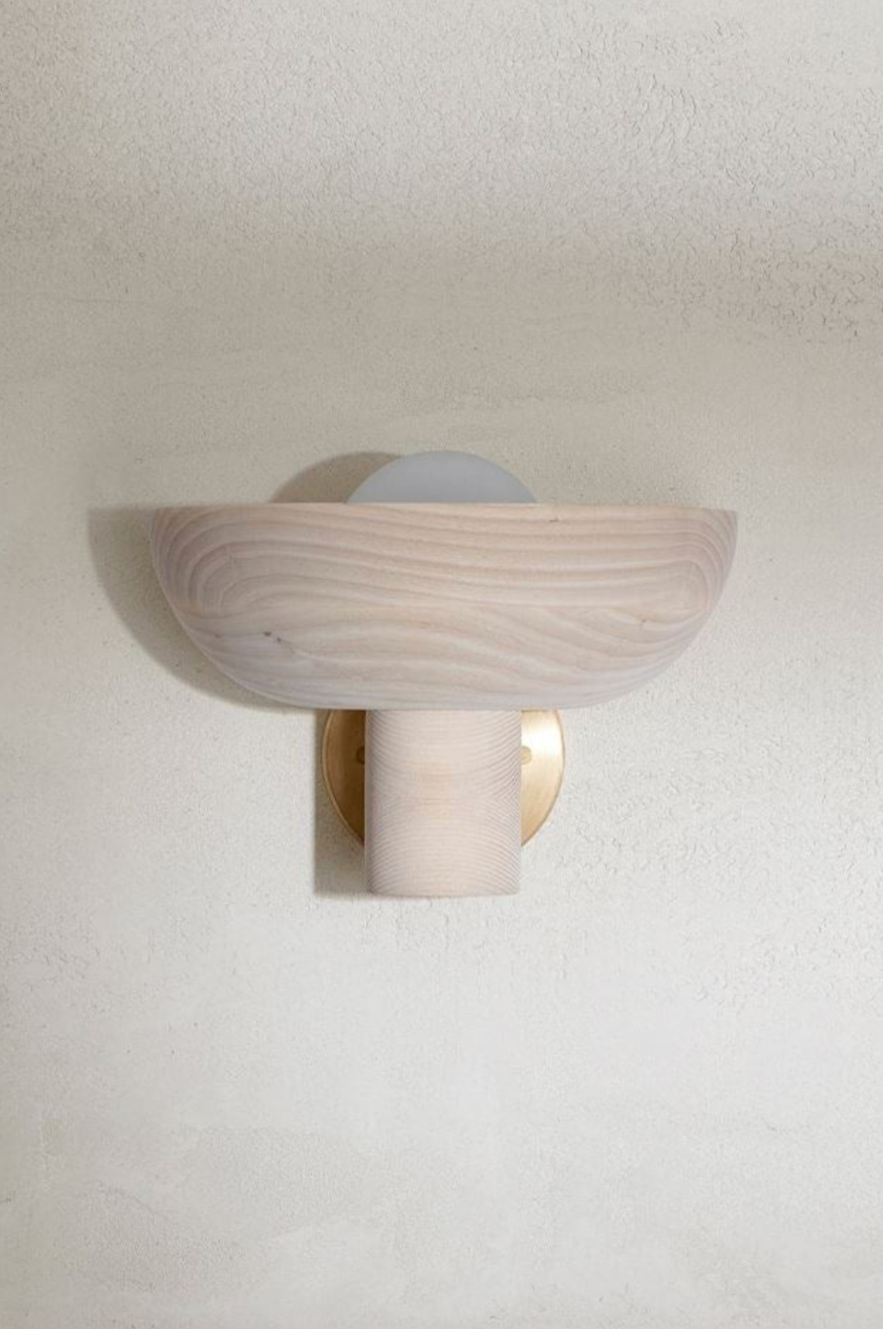 Wall-mounted light fixture with a wooden design on a plain wall.