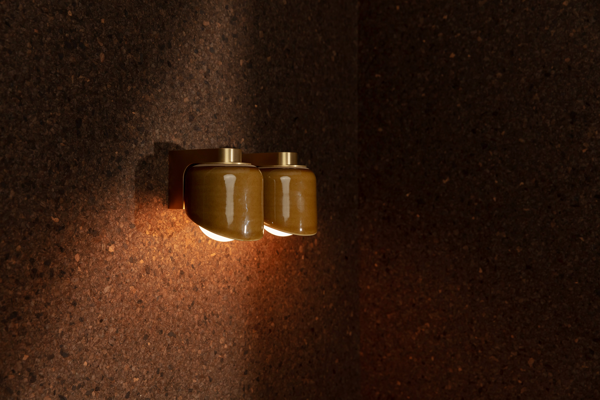 Wall-mounted light fixture casting a warm glow on a textured wall.
