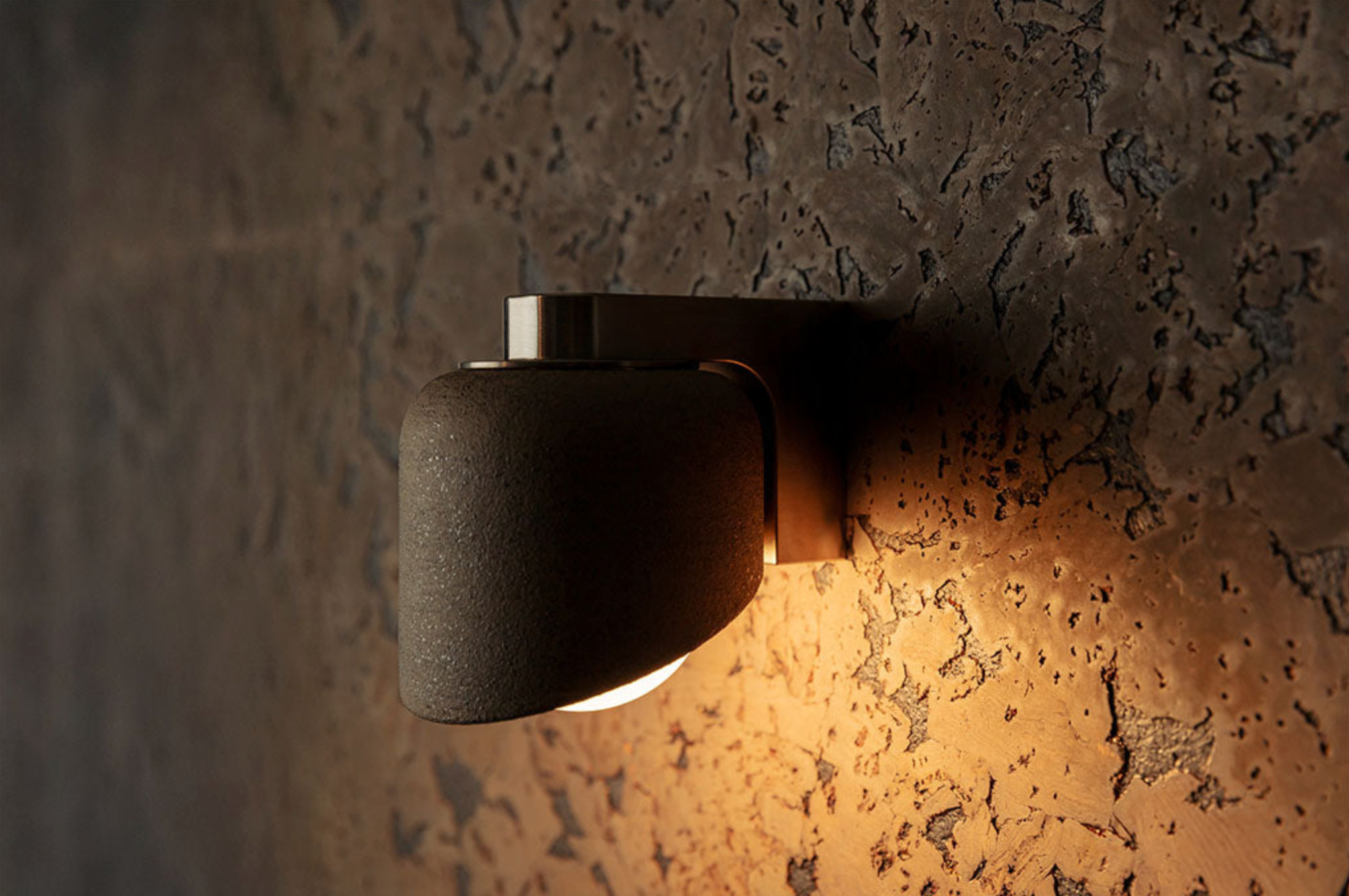 Wall-mounted light fixture casting a warm glow on a textured wall.