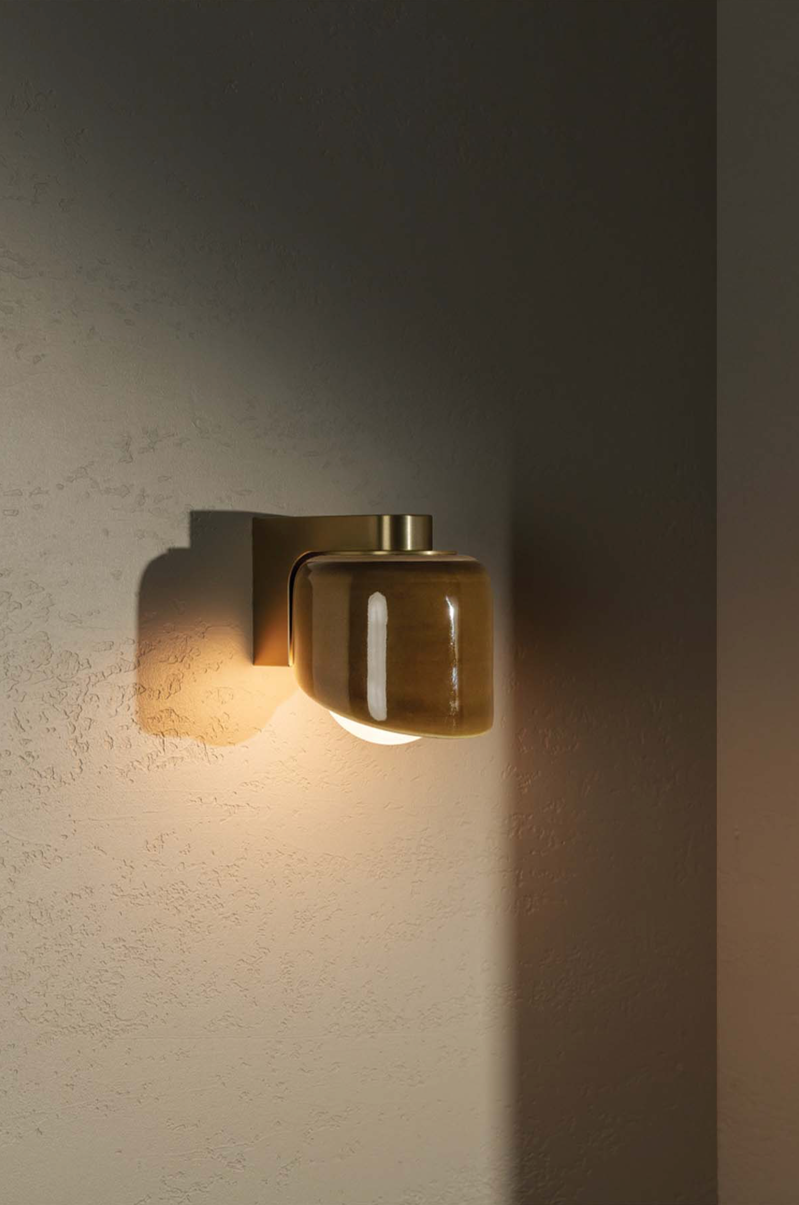 Wall-mounted light fixture with a warm glow on a textured wall.