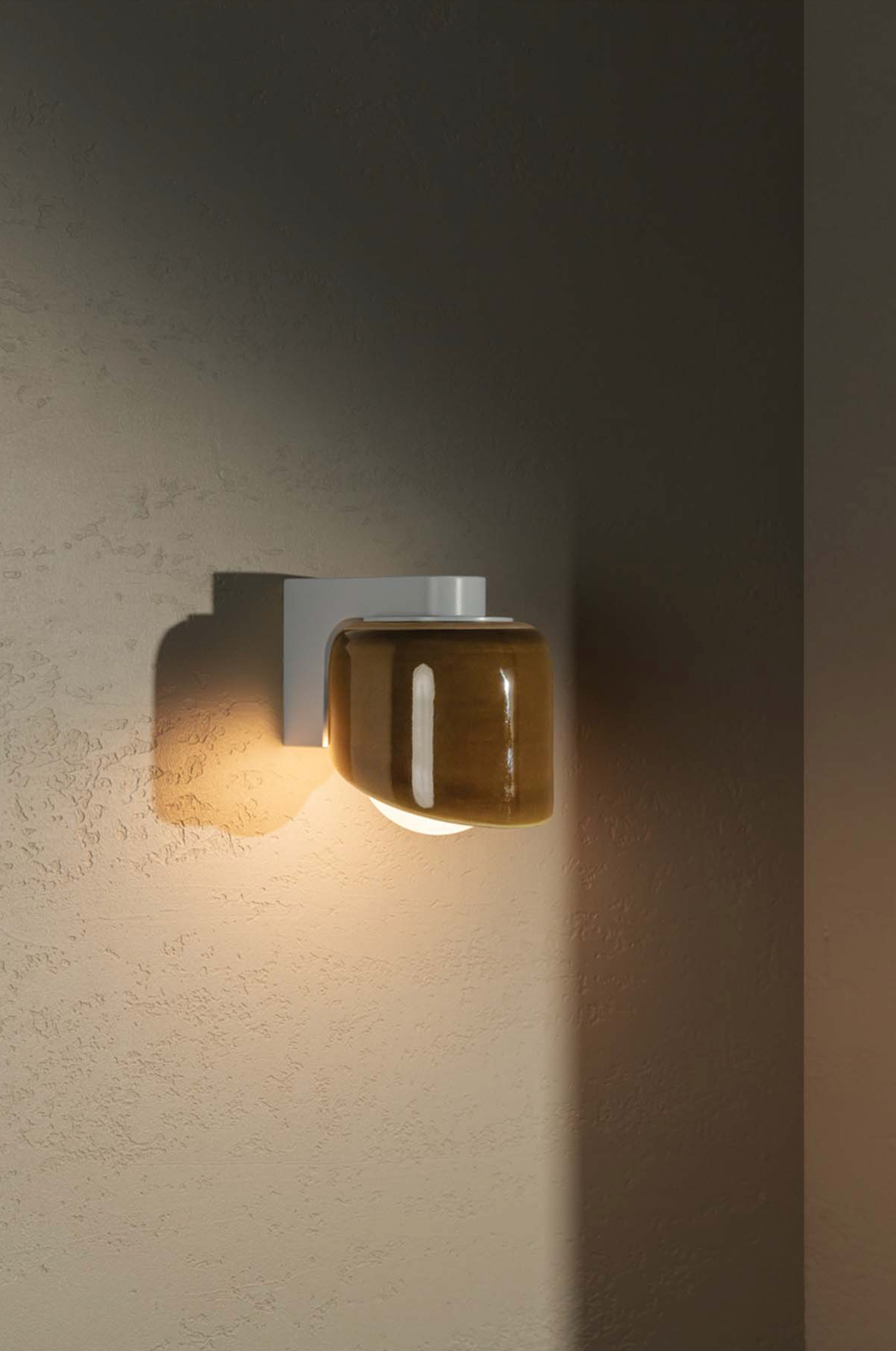 Wall-mounted light fixture with glass cover on a textured wall