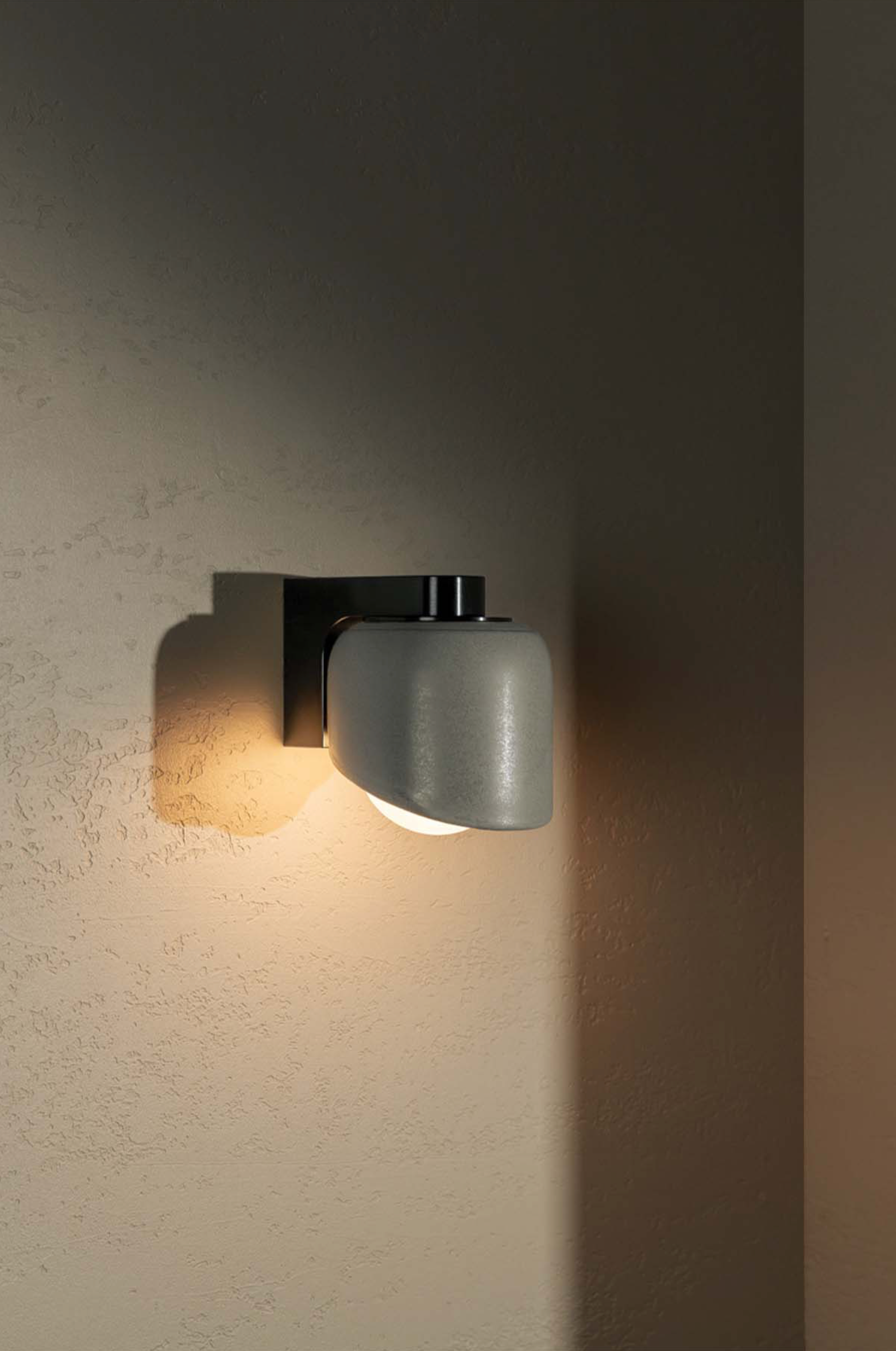 Wall-mounted light fixture casting a warm glow on a textured wall.