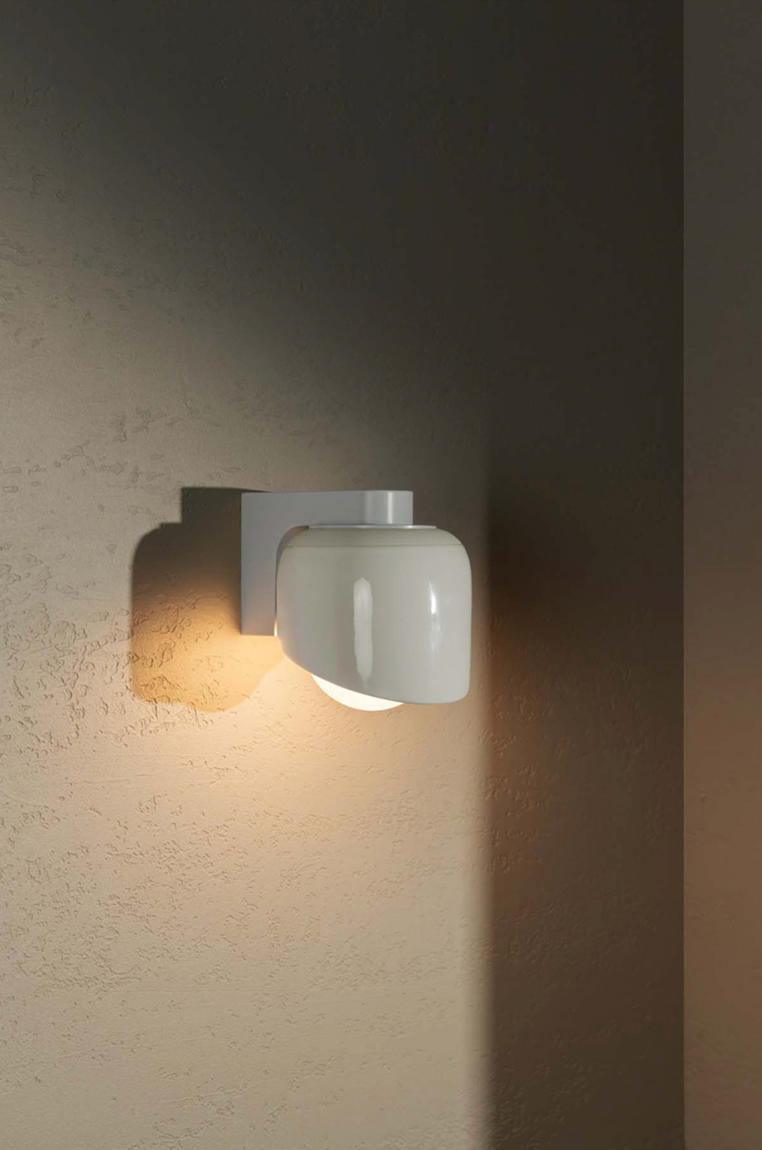 Wall-mounted light fixture casting a warm glow on a textured wall.