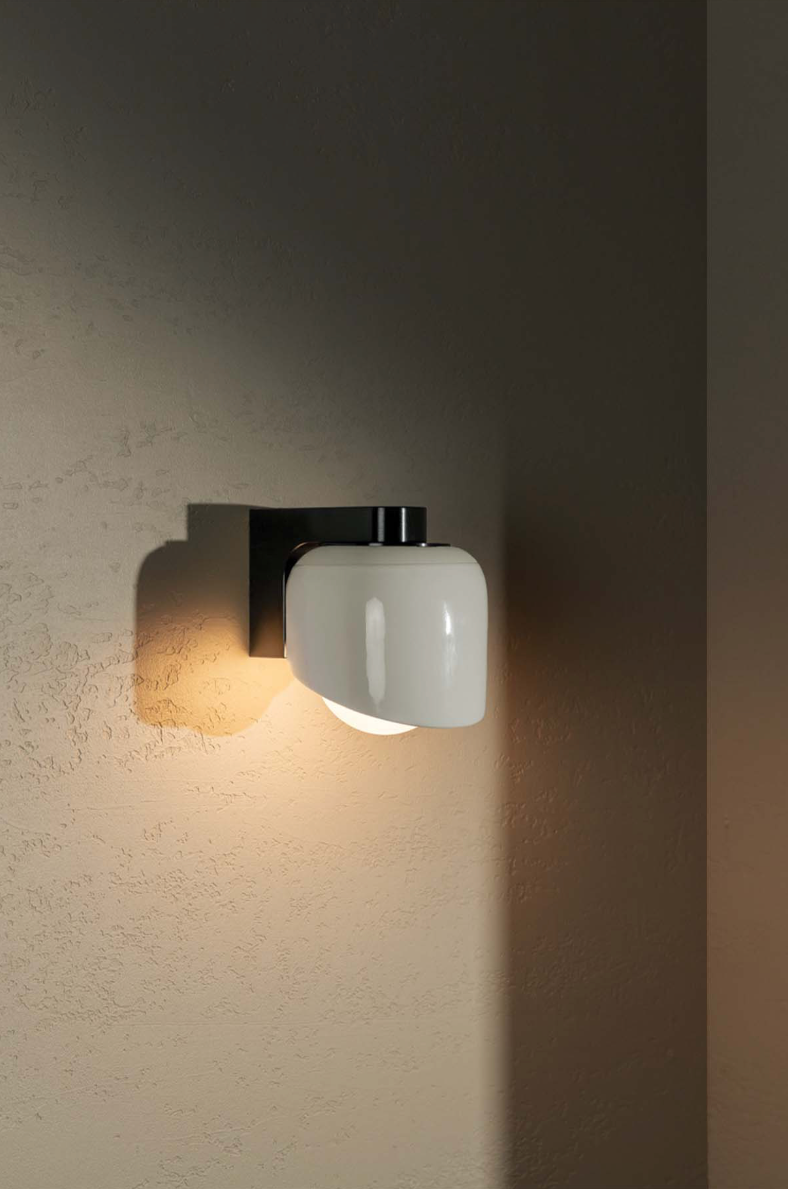 Wall-mounted light fixture casting a warm glow on a textured wall.