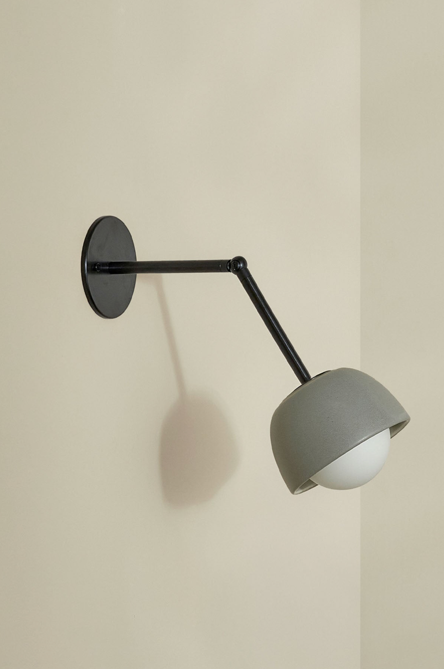 Wall-mounted lamp with a grey shade and black arm on a beige wall