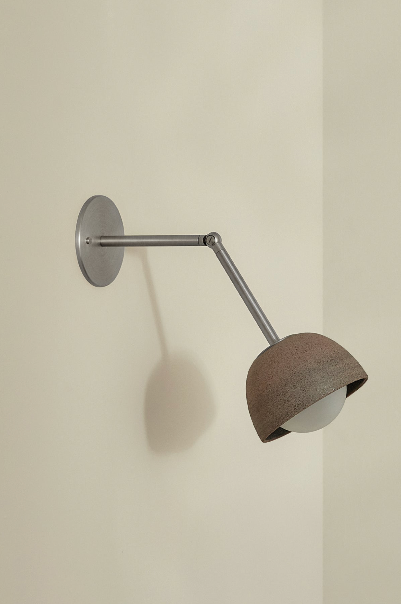 Wall-mounted lamp with a concrete shade on a plain wall