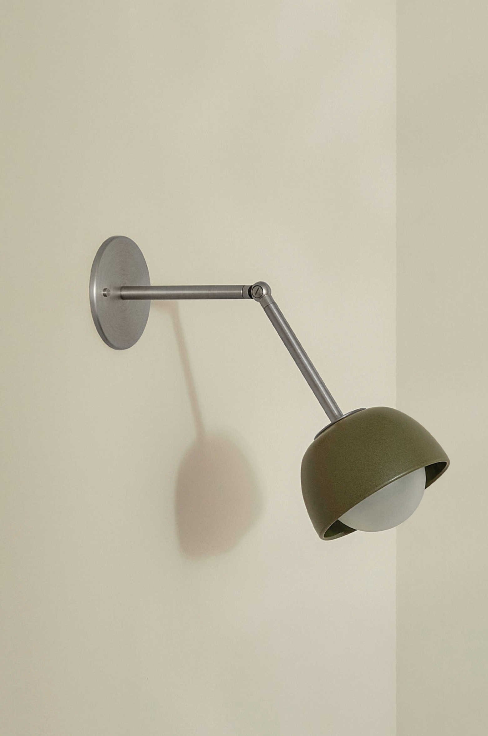 Wall-mounted ceramic lamp with a green shade on a plain wall