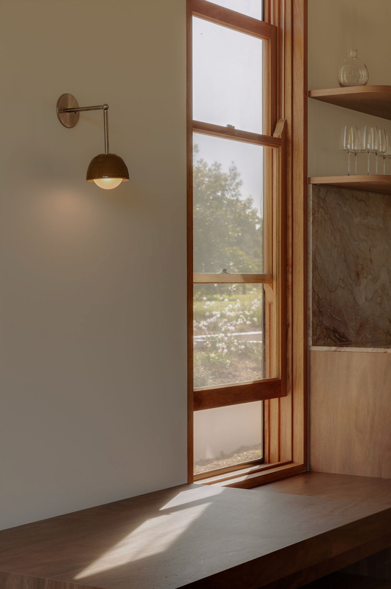Modern interior with a large window, wall-mounted ceramic light fixture, and wooden bench.