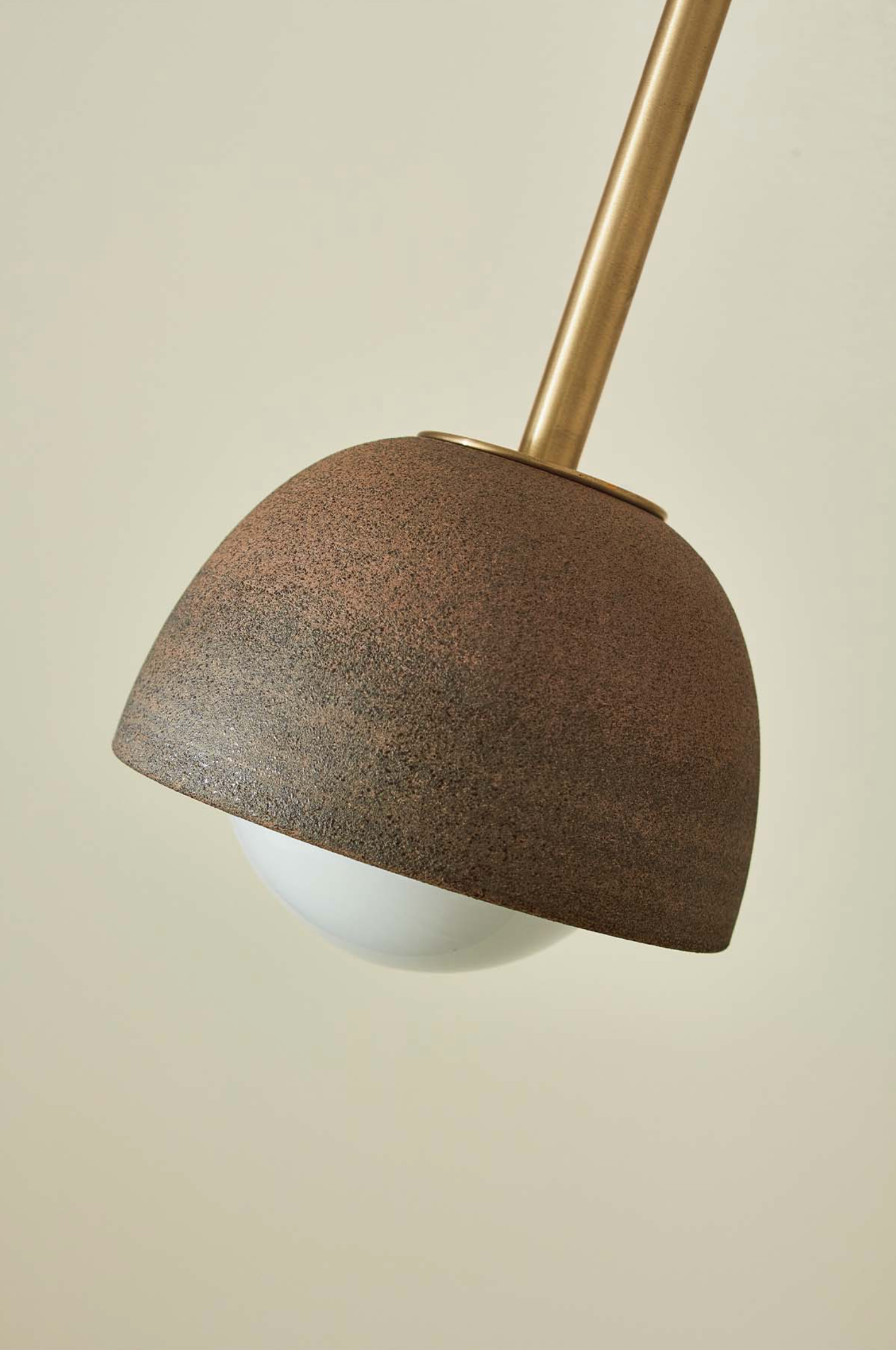 Lamp with brown textured ceramic shade and gold arm on a beige background