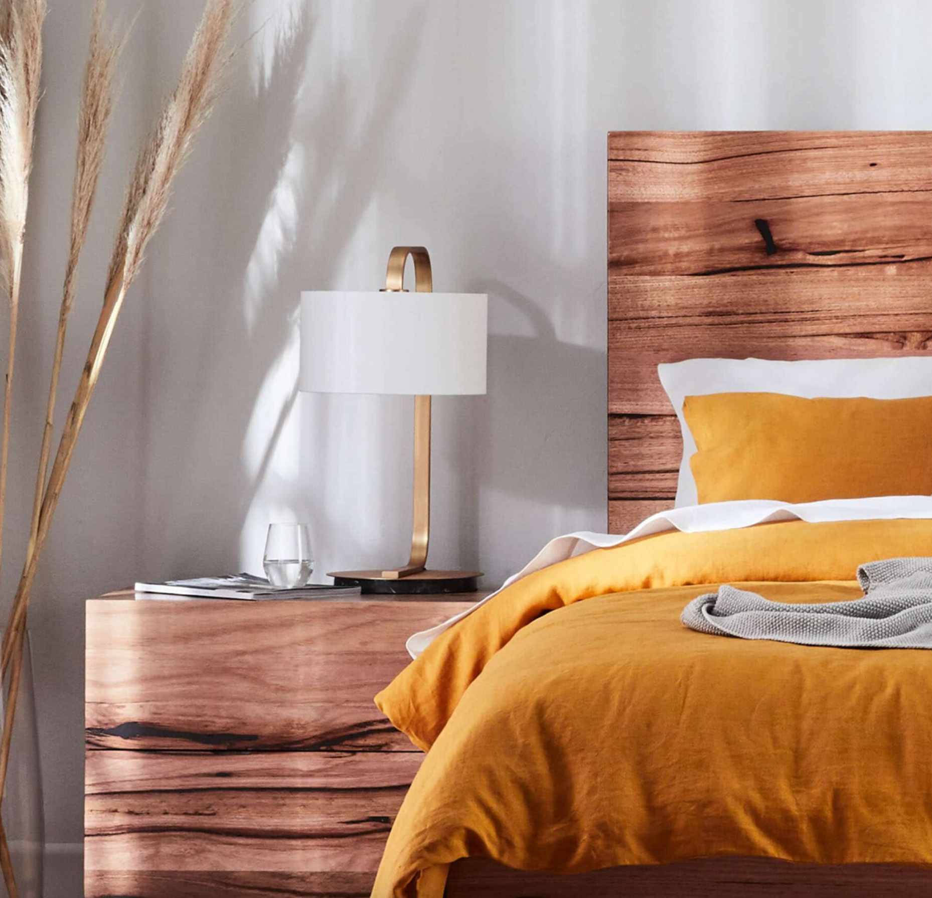 Bedroom with wooden headboard, yellow bedding, and lamp on nightstand.
