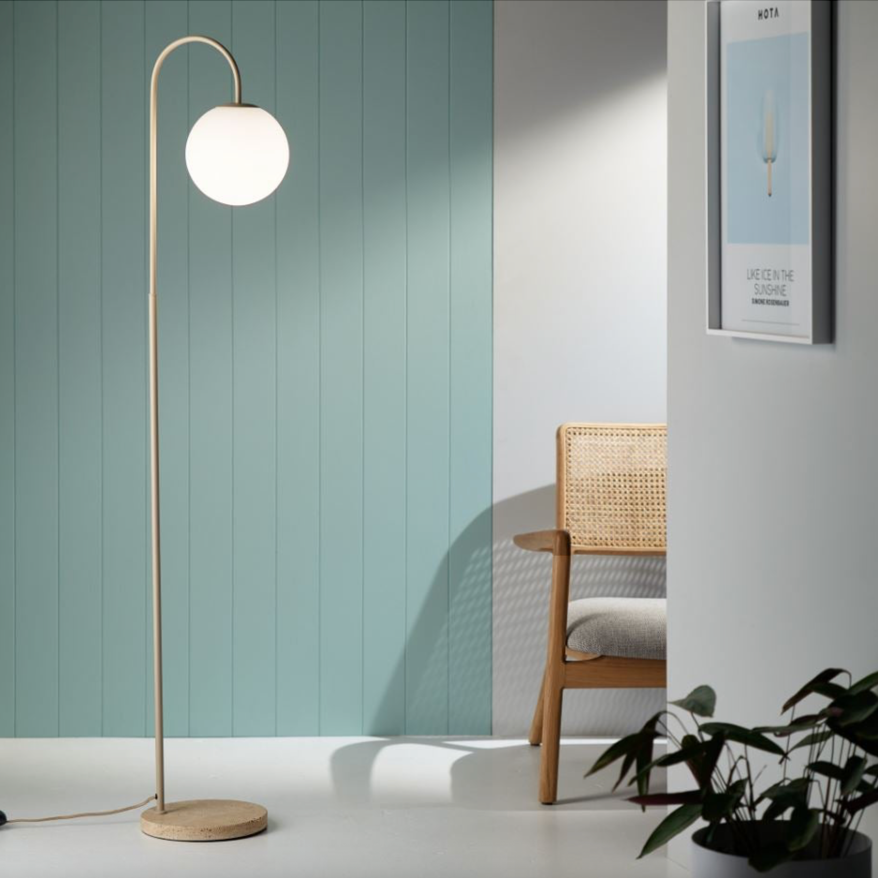 Modern floor lamp with a round white light bulb in a room with a chair and plant.