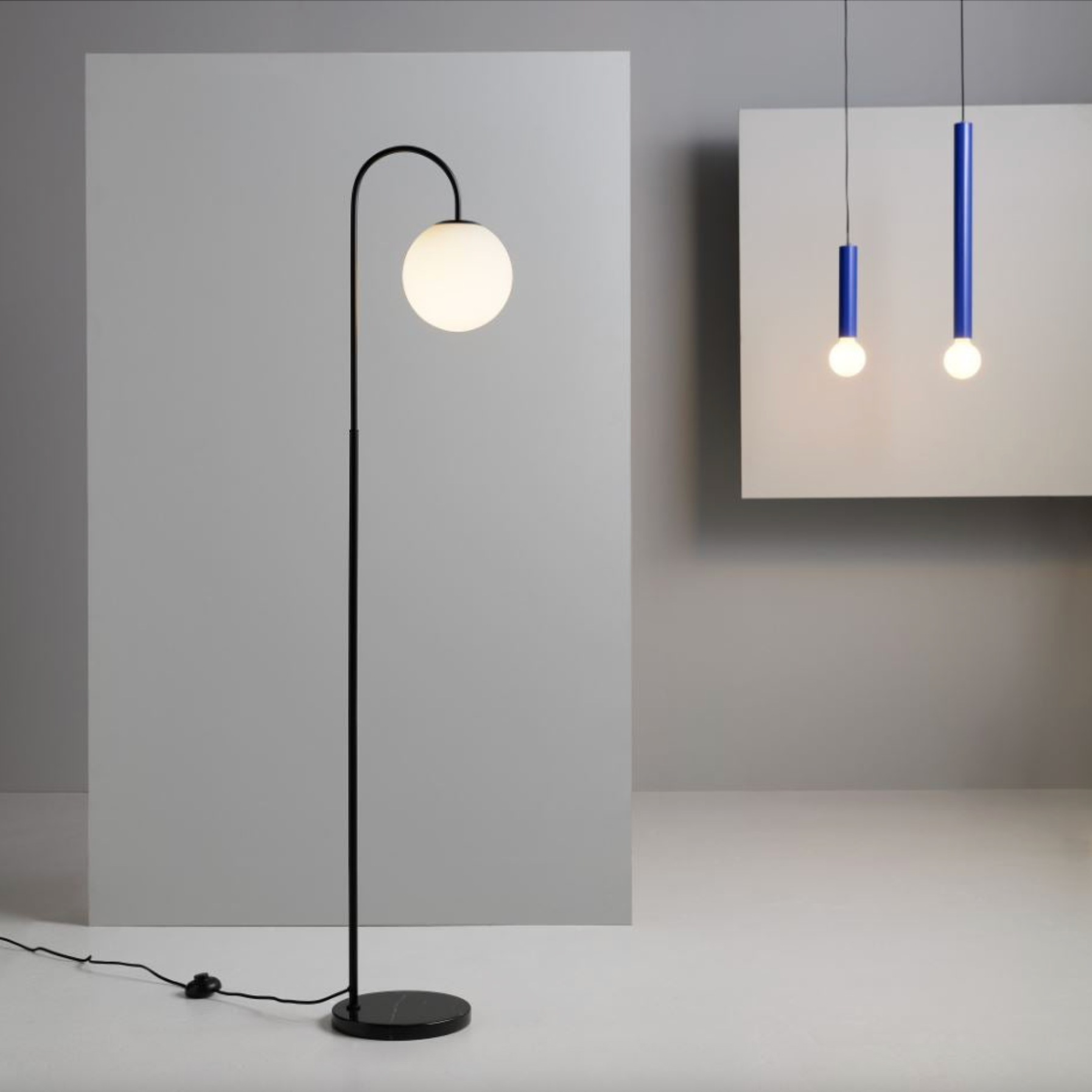 Modern black floor lamp with a round white light bulb on a neutral background