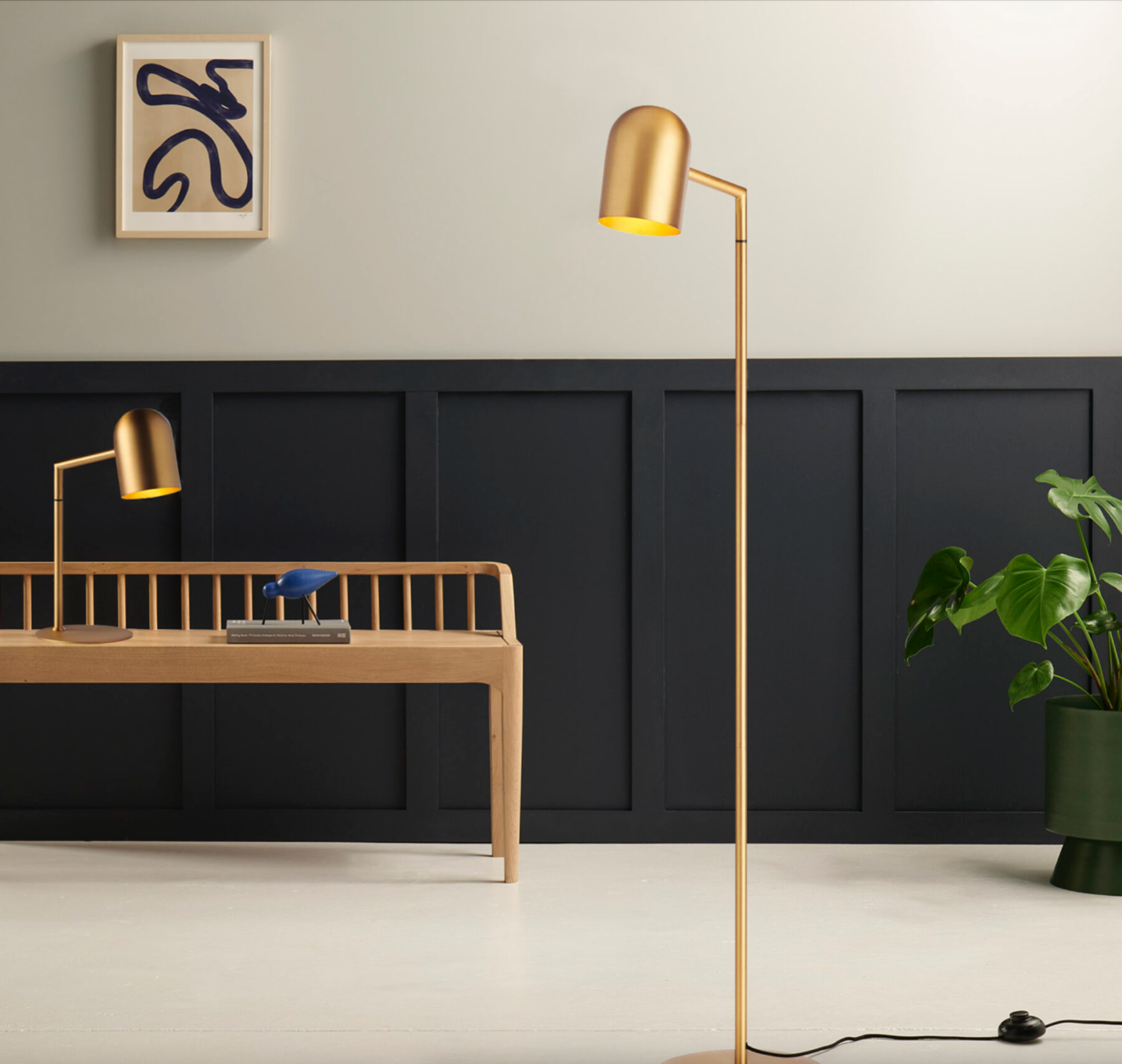 Modern interior with a gold floor lamp, desk, and black paneling.