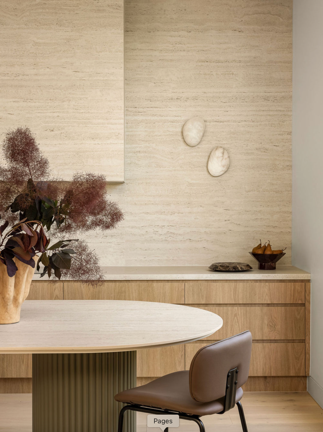 Modern interior with a round wooden table and chair against a textured wall.