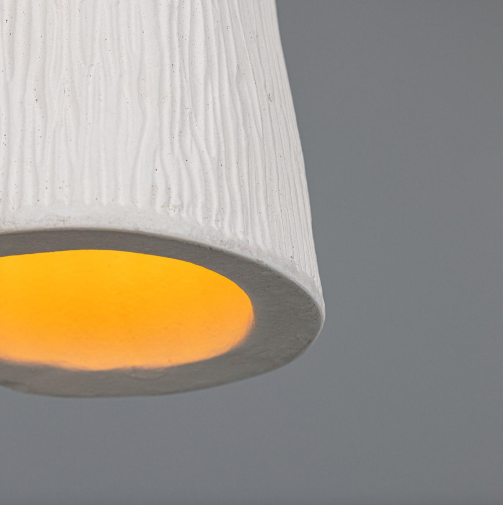 Close-up of a textured white lampshade with a yellow interior on a gray background