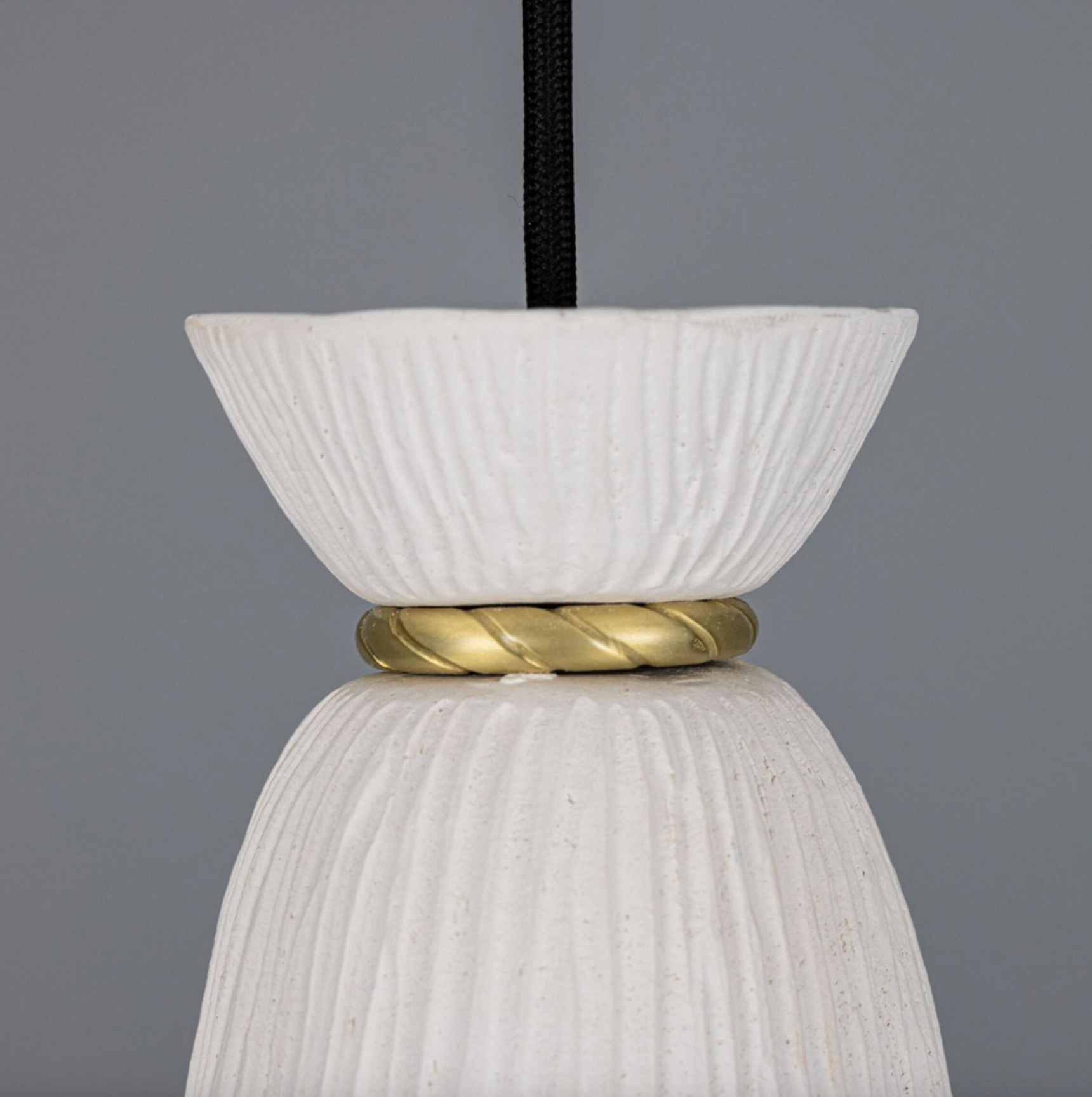 White textured pendant light with gold accent on a gray background