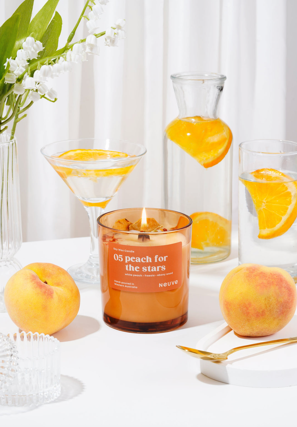 Candle labeled '05 peach for the stars' with peaches and a glass container in the background.